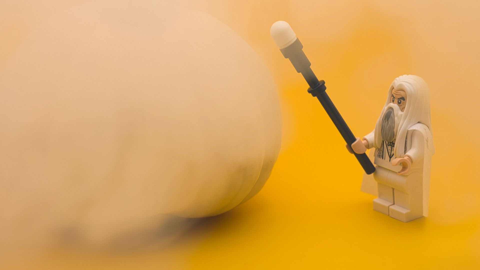 a lego figurine holding a large object on a yellow background