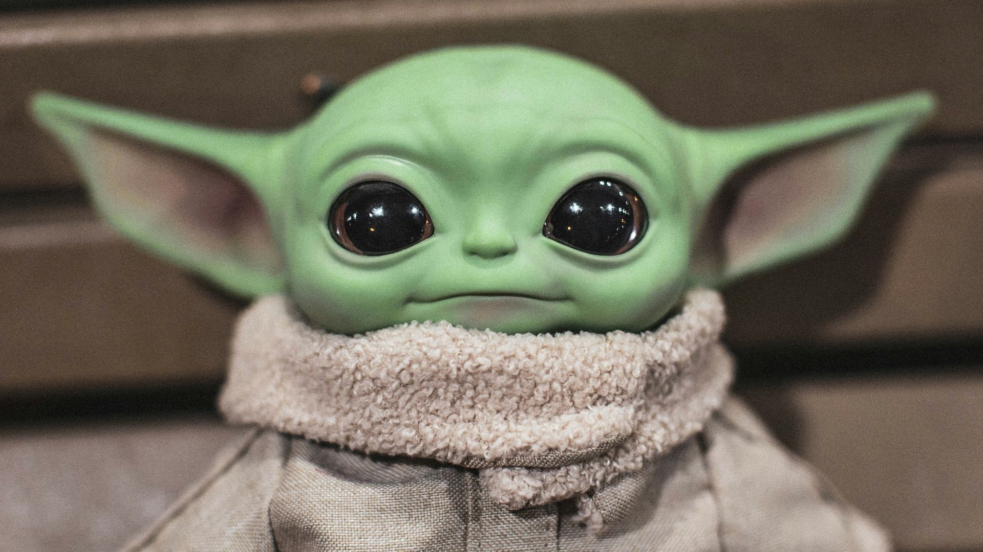 green frog plush toy on brown textile