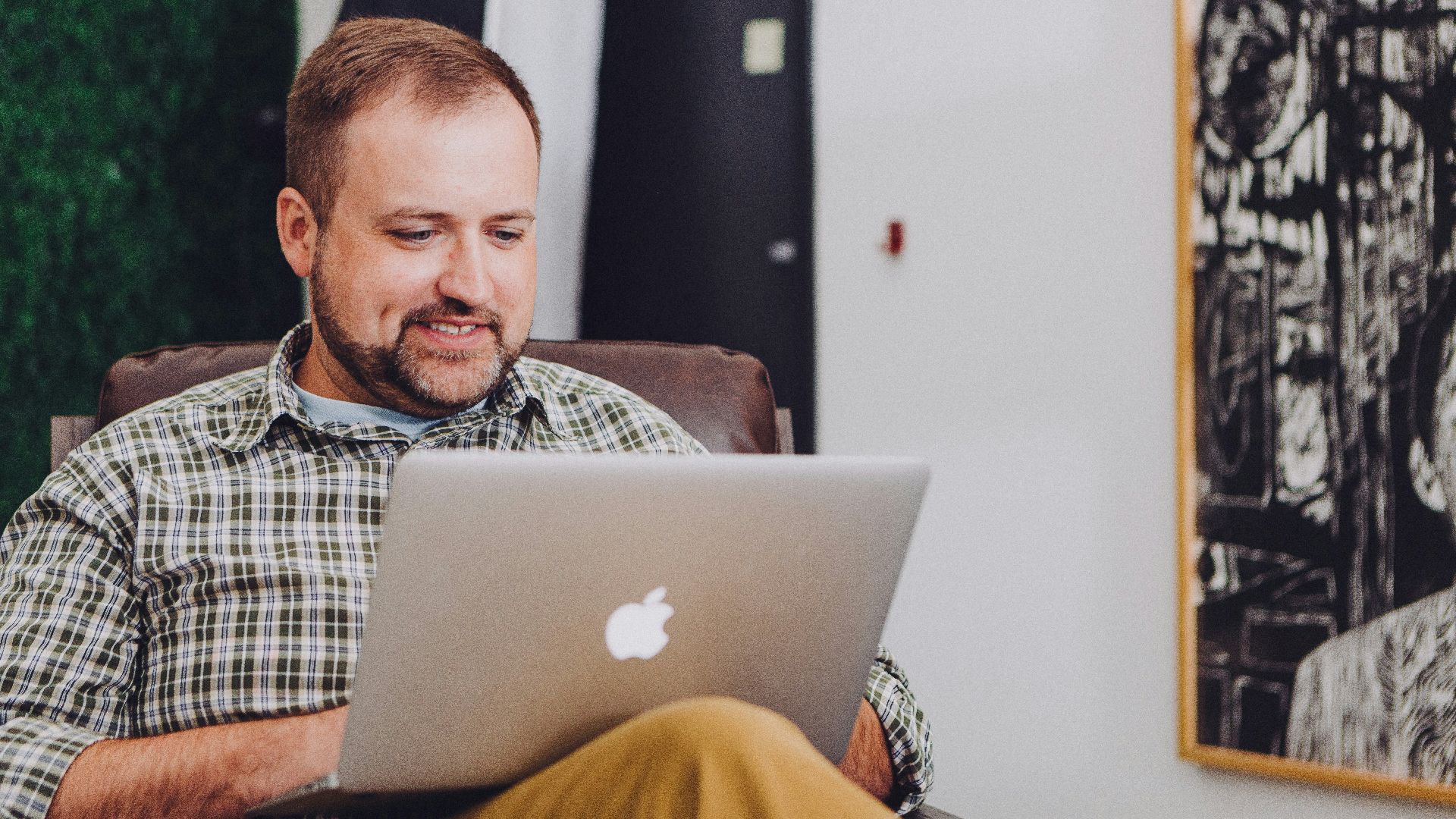 man smiling and using MacBook