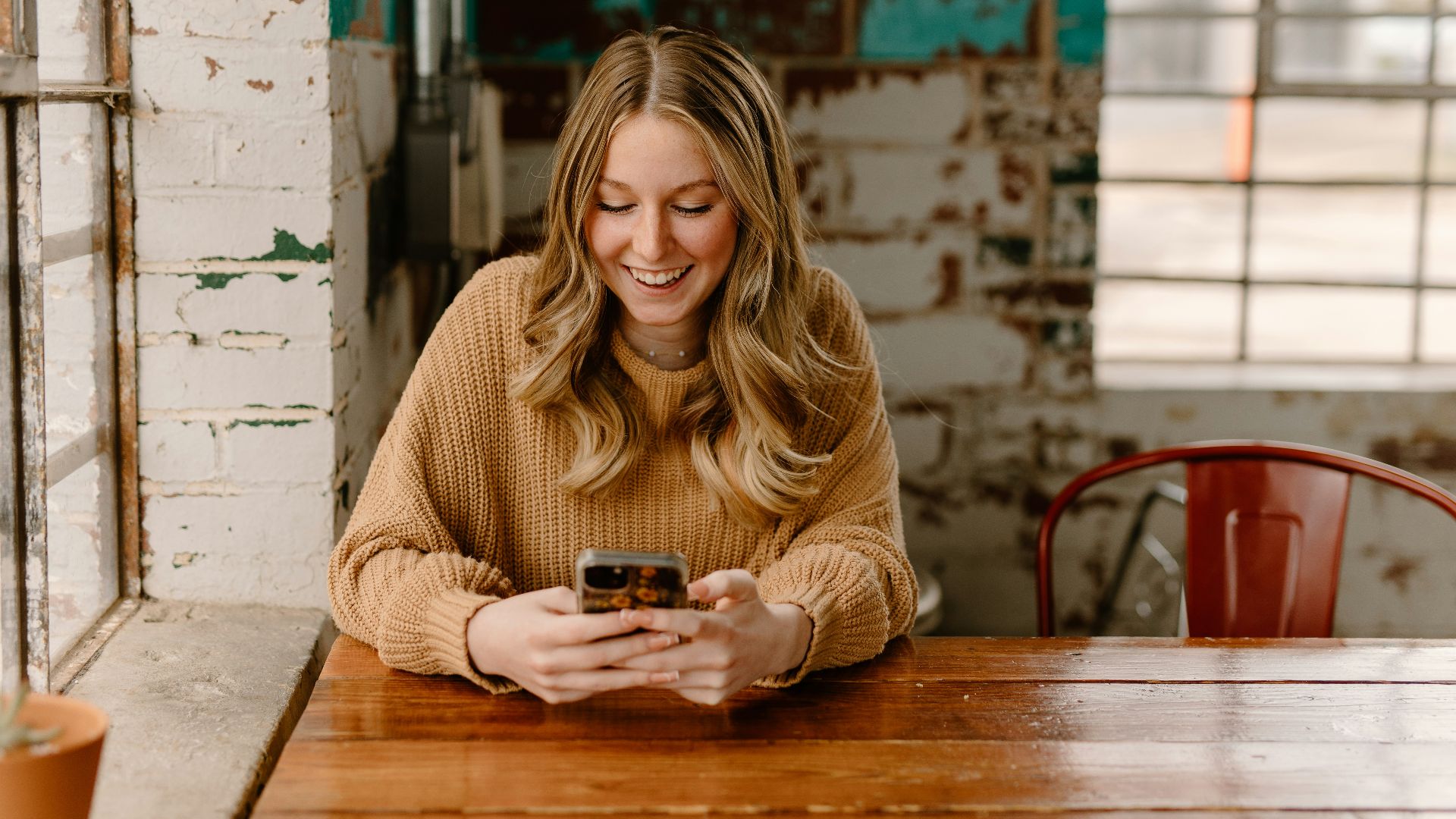 a woman sitting at a table looking at her cell phone