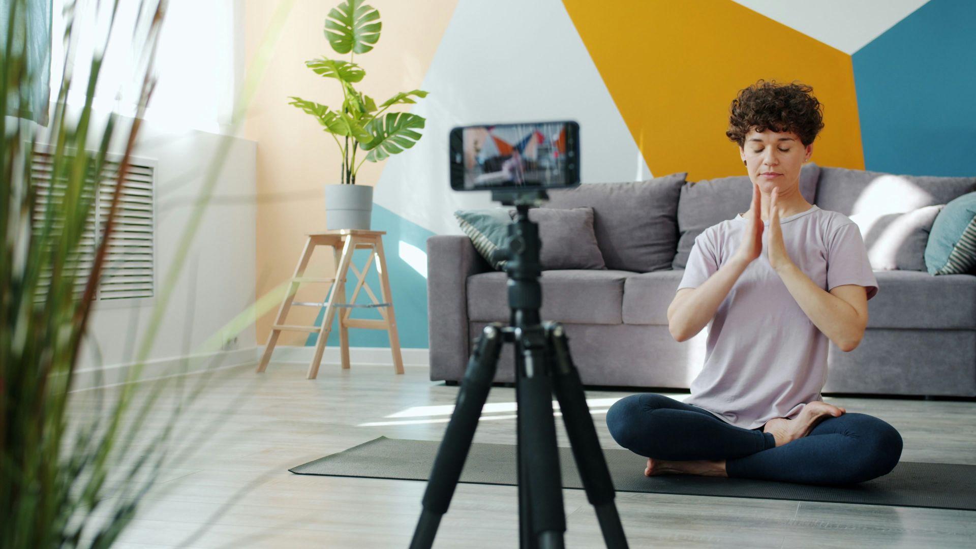 Woman meditating in front of a phone camera.