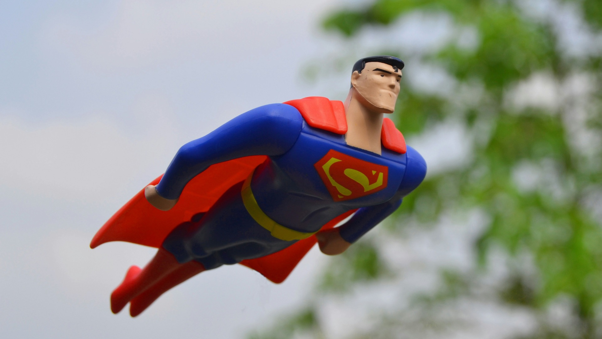 Superman flying near green grass