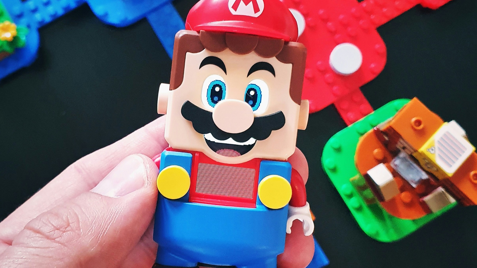a hand is holding a toy of a mario