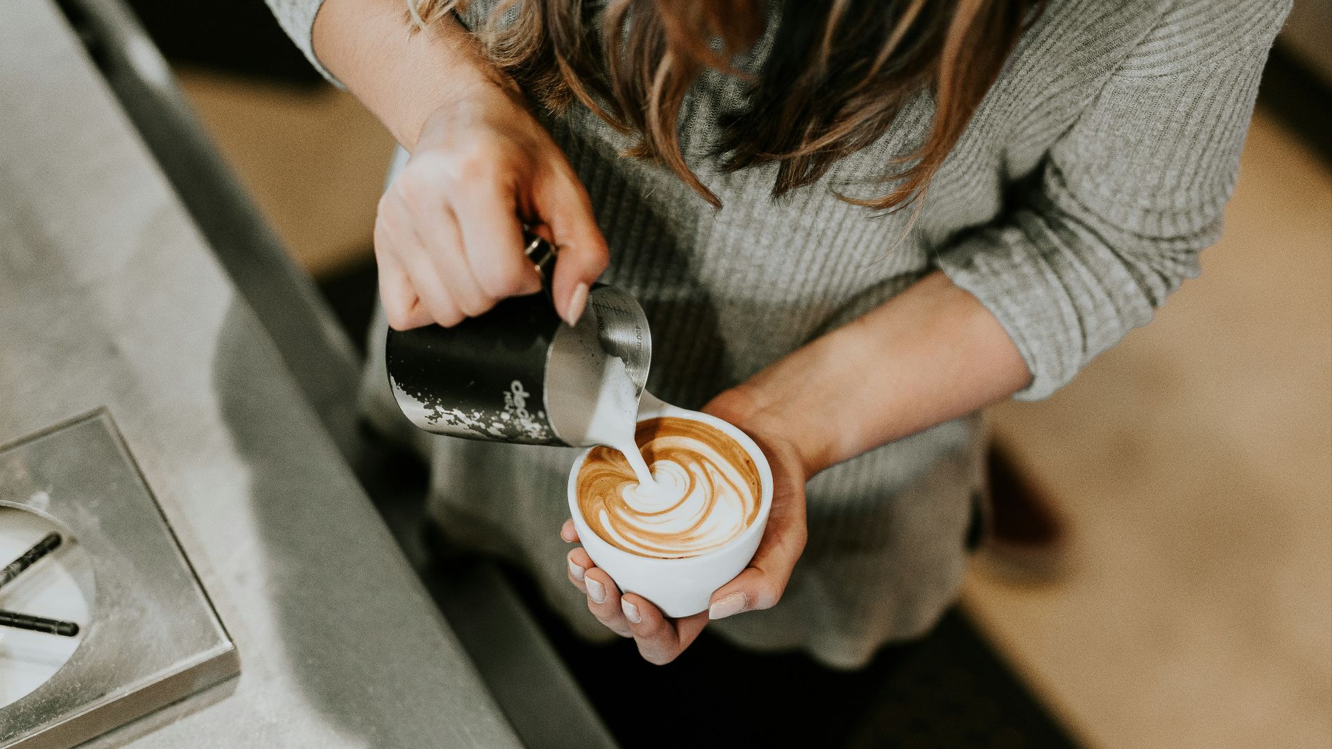 person pouring cup of coffee in white ceramic cup