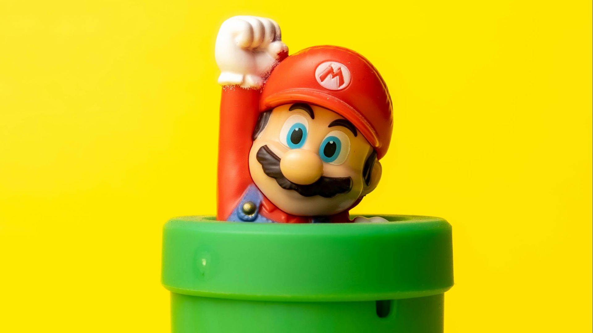 a toy mario in a green container on a yellow background