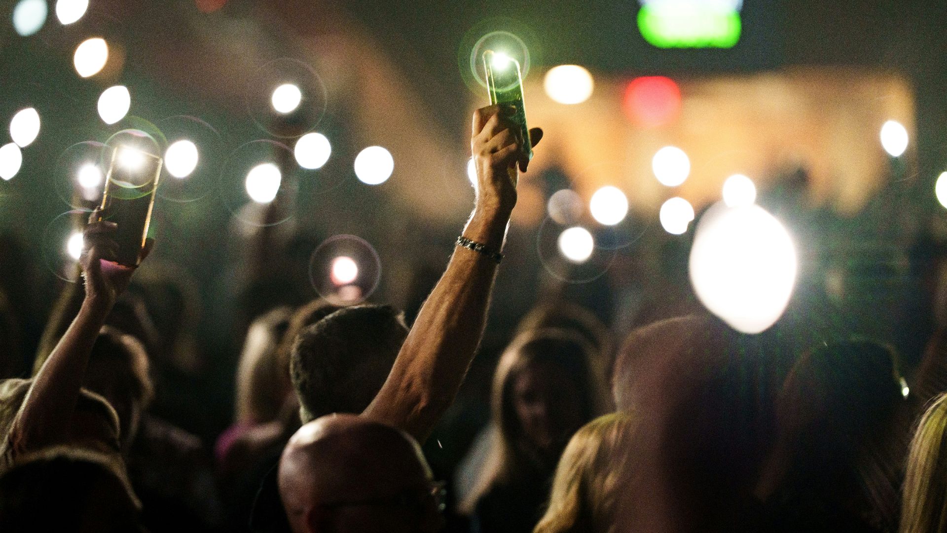 a crowd of people holding up a green light