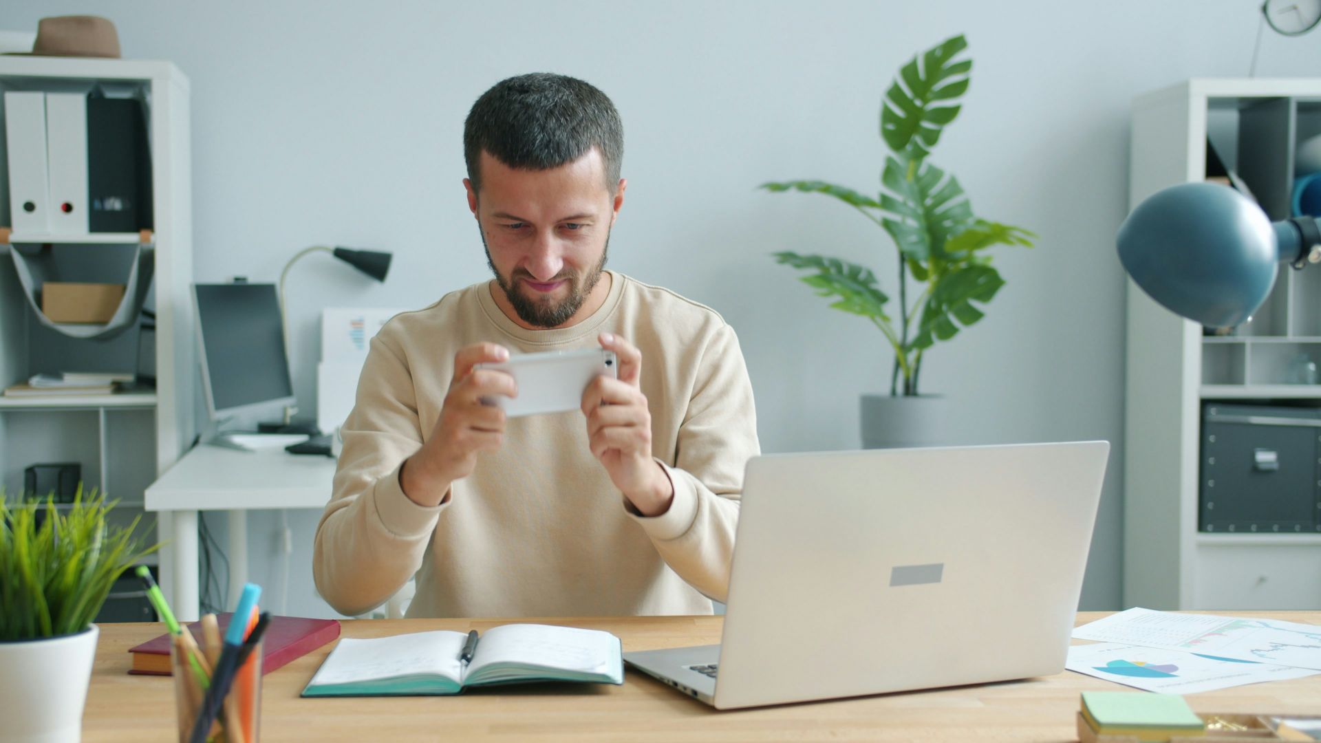 Man holding a card at a desk with laptop.