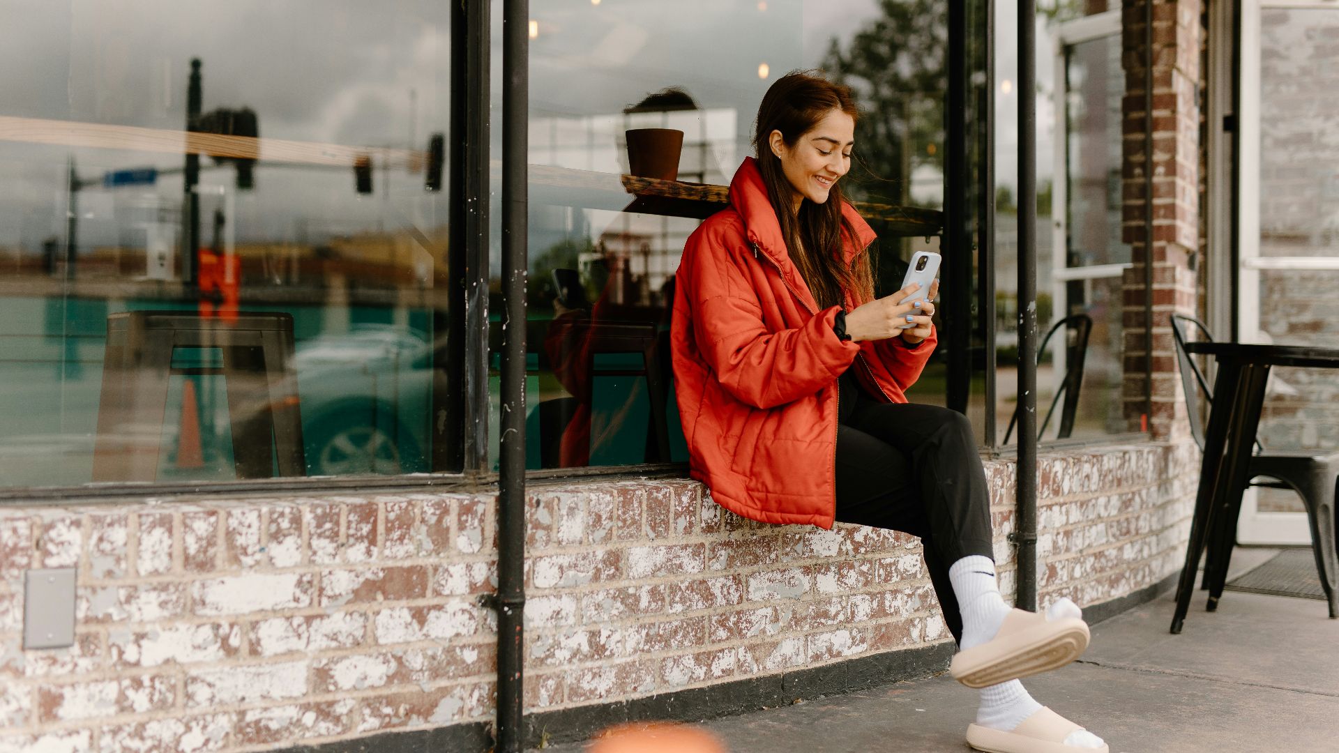 a woman sitting on a window sill looking at her cell phone