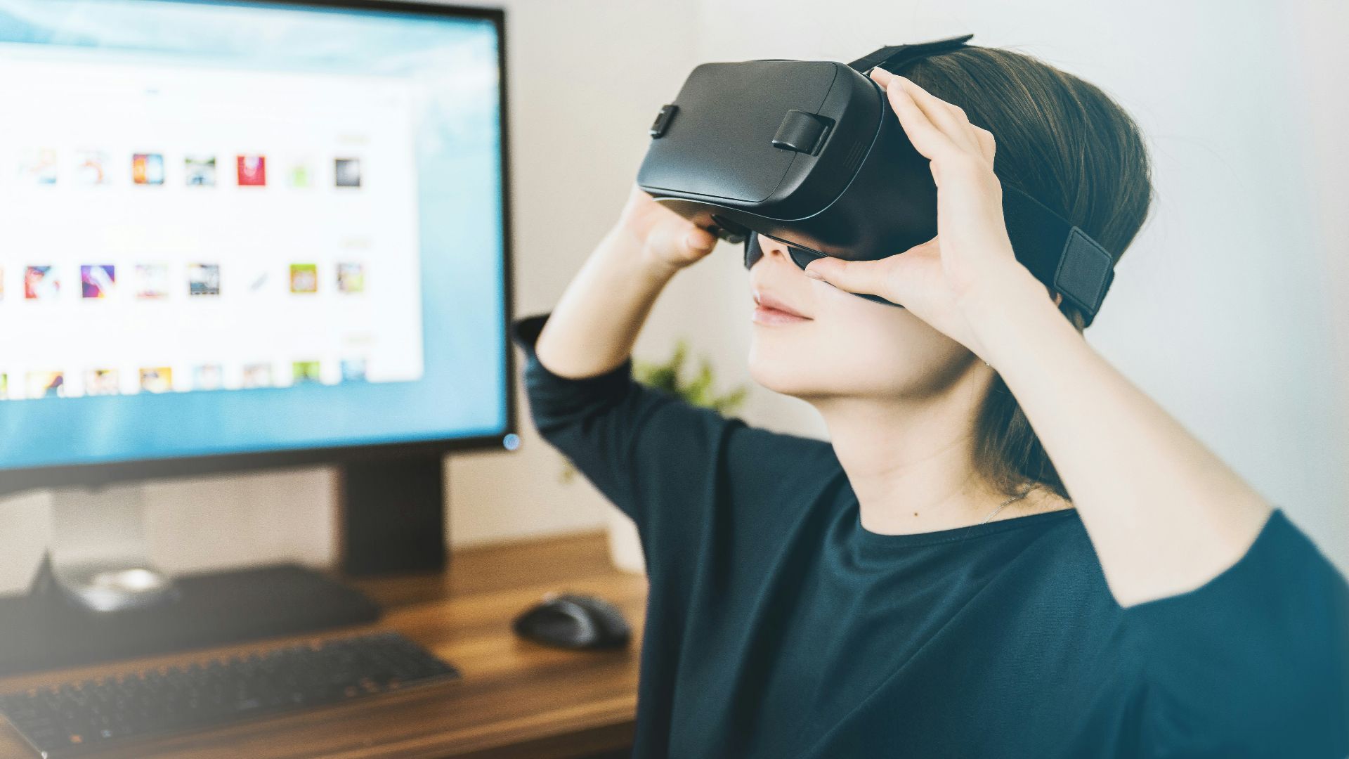 woman using black VR headset beside computer