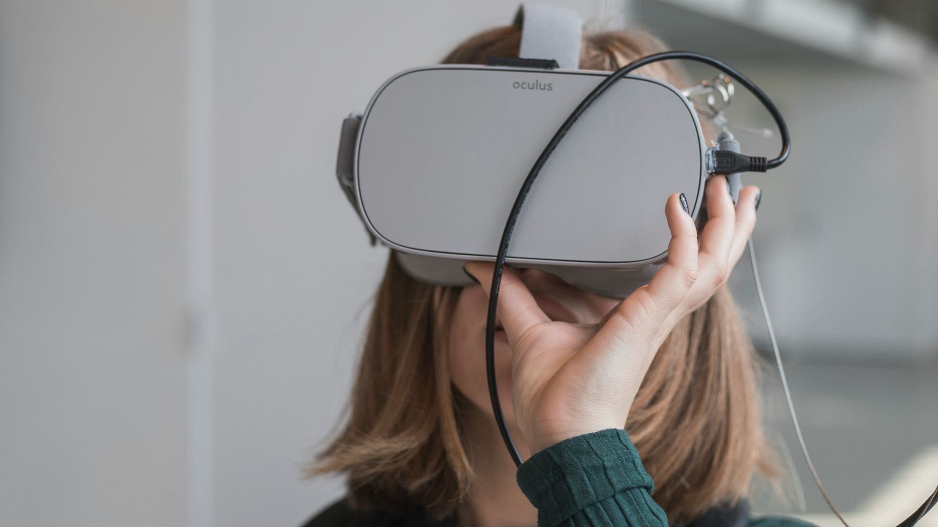 woman in black sweater holding white and black vr goggles