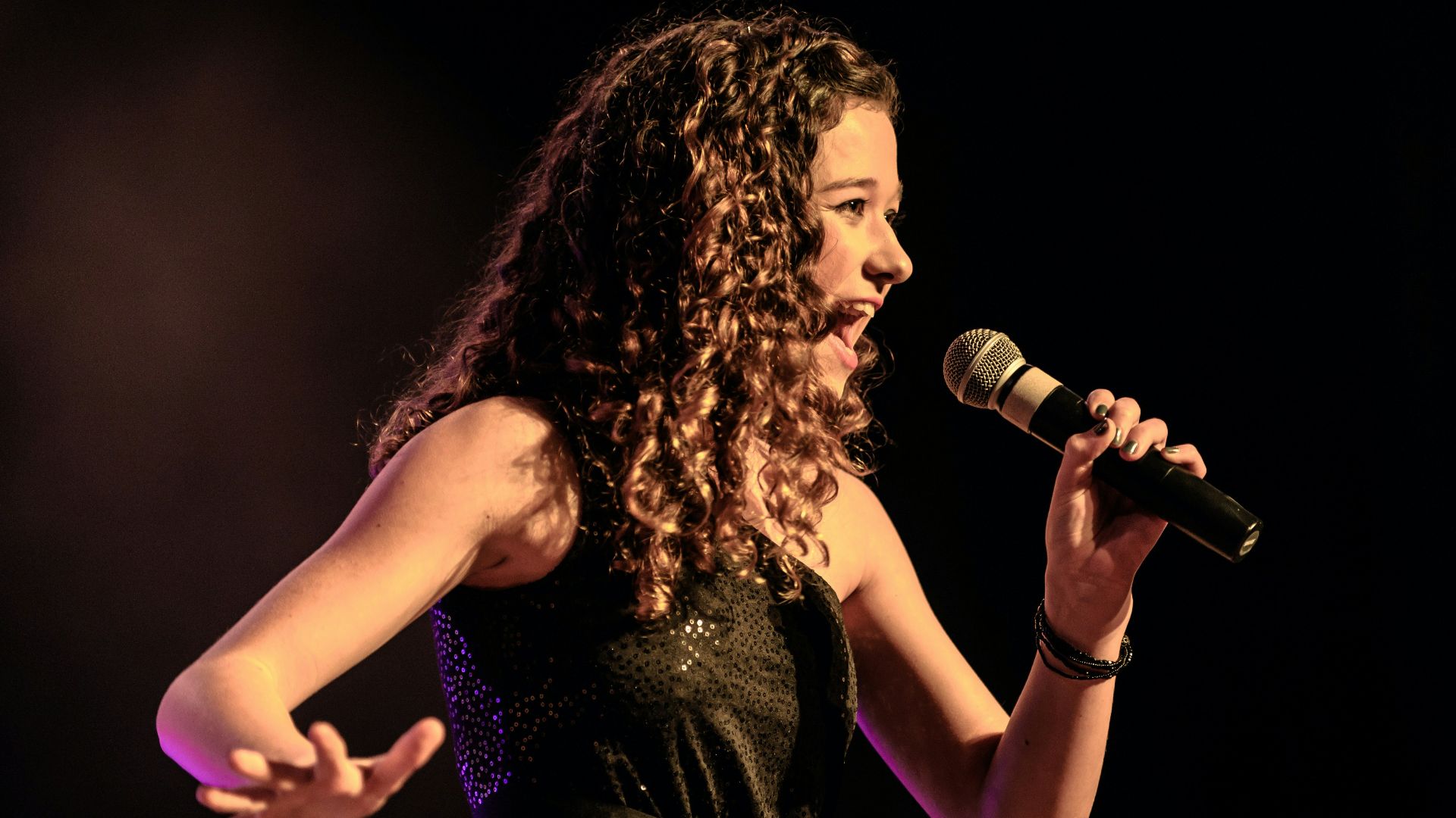 woman in black sleeveless dress singing