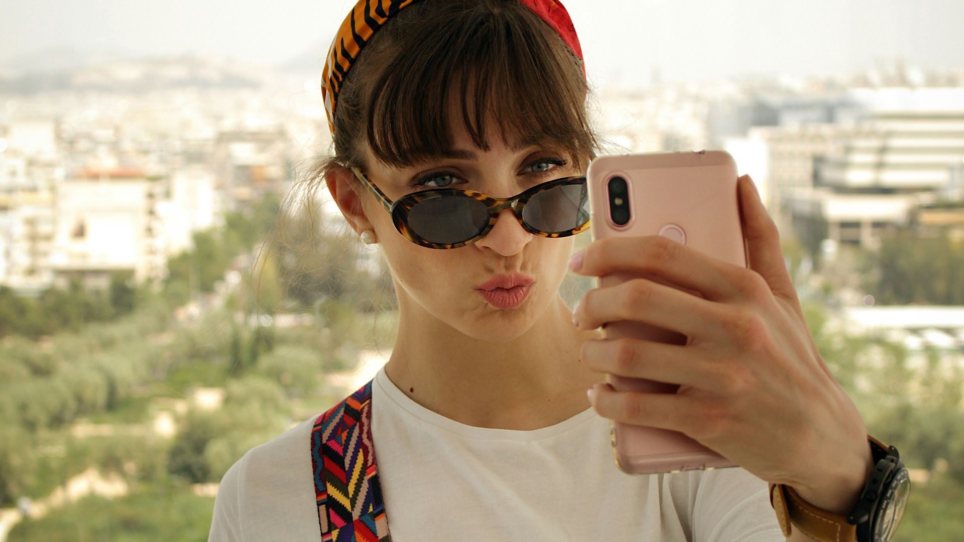 woman pouting her lips while holding smartphone in front of her face