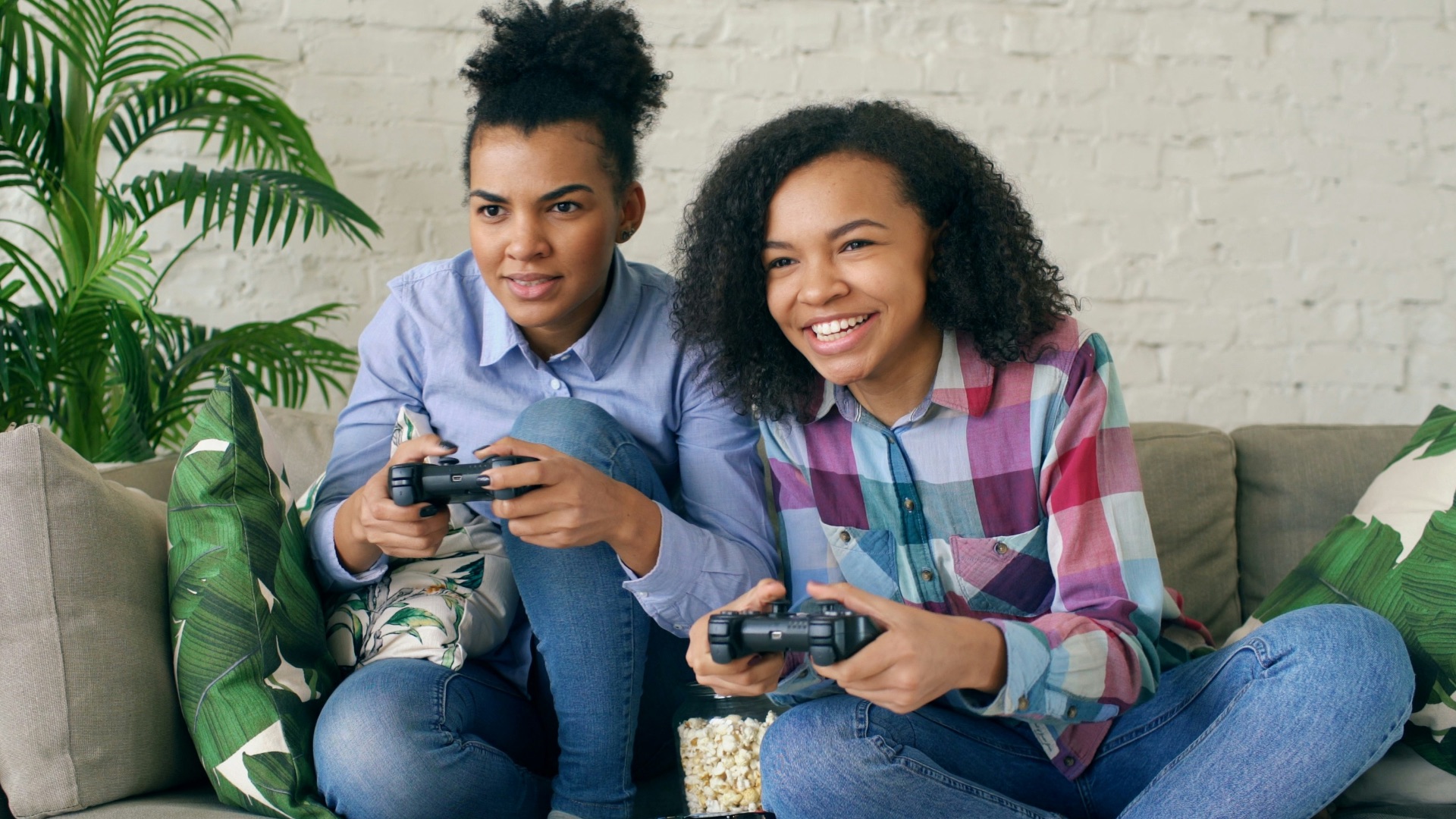 Two women playing video games on a couch.