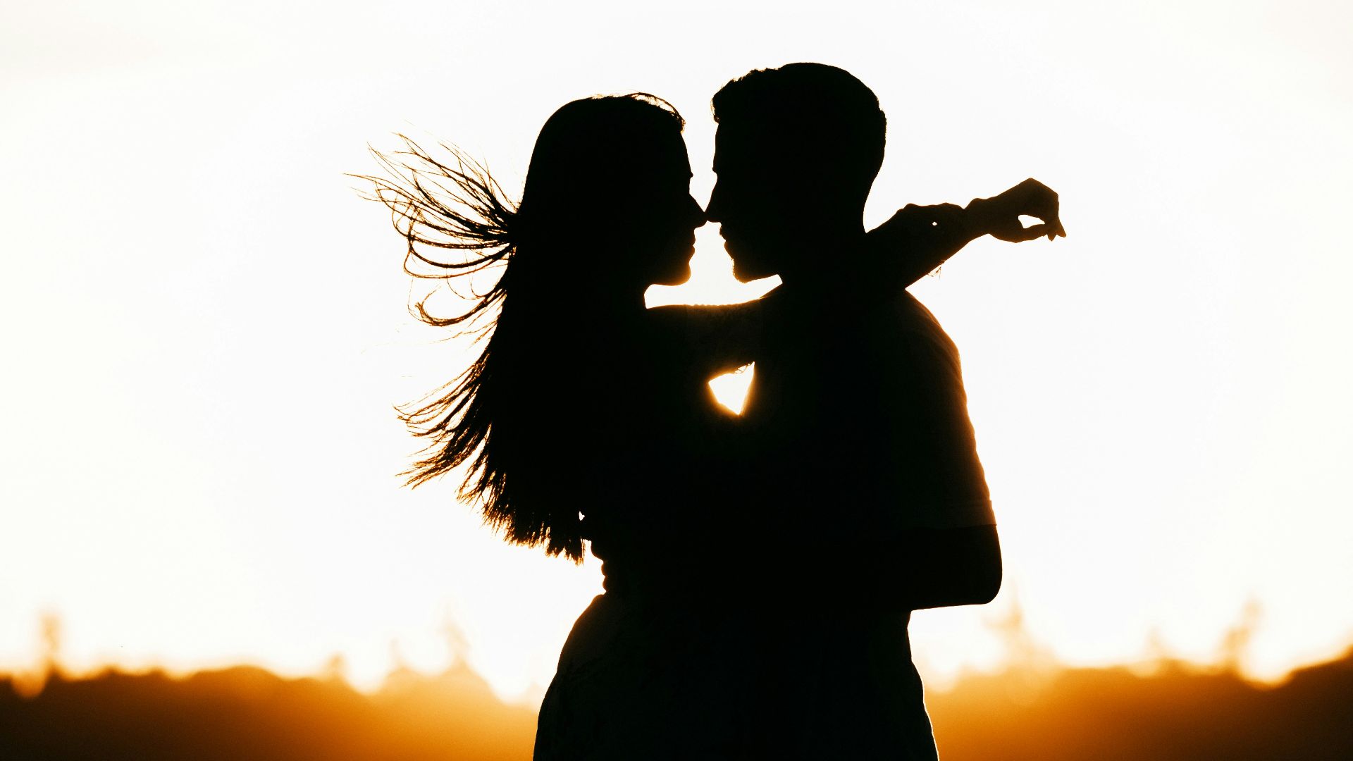 silhouette of woman standing on beach during sunset