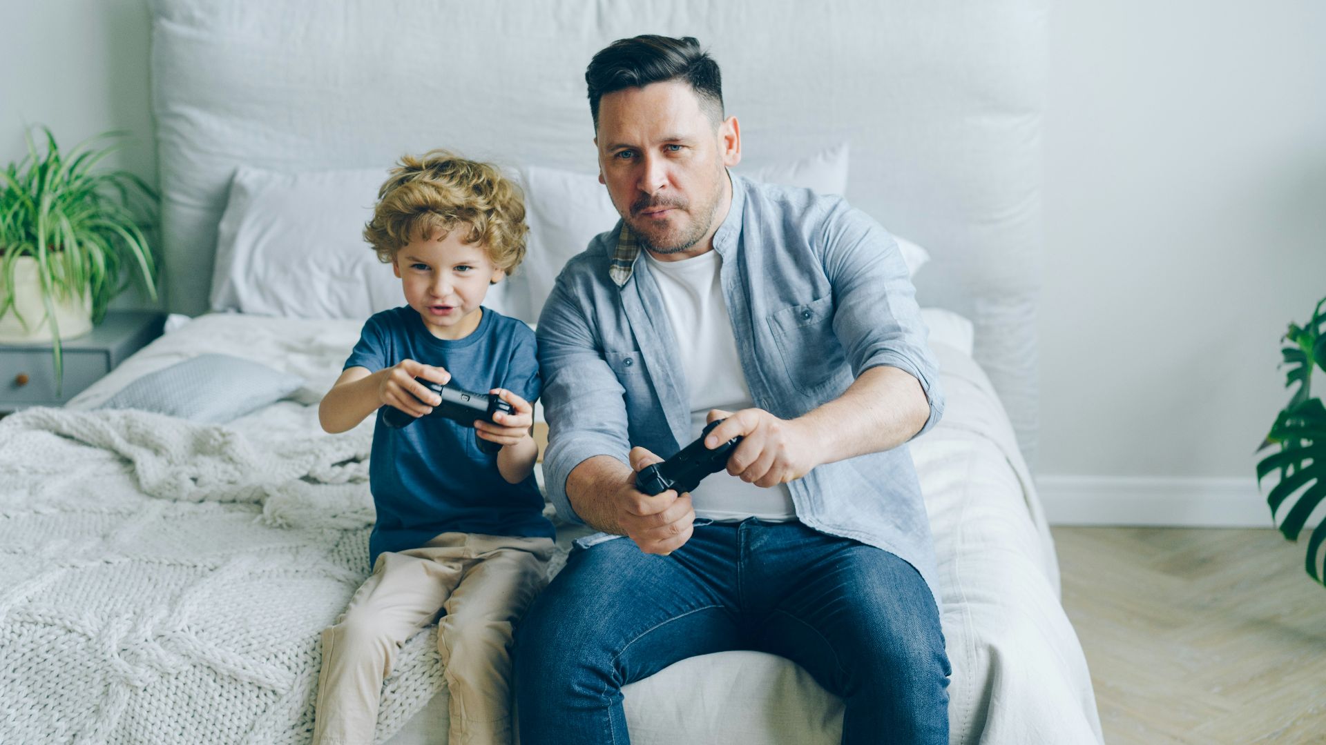 a man sitting on a bed next to a little boy