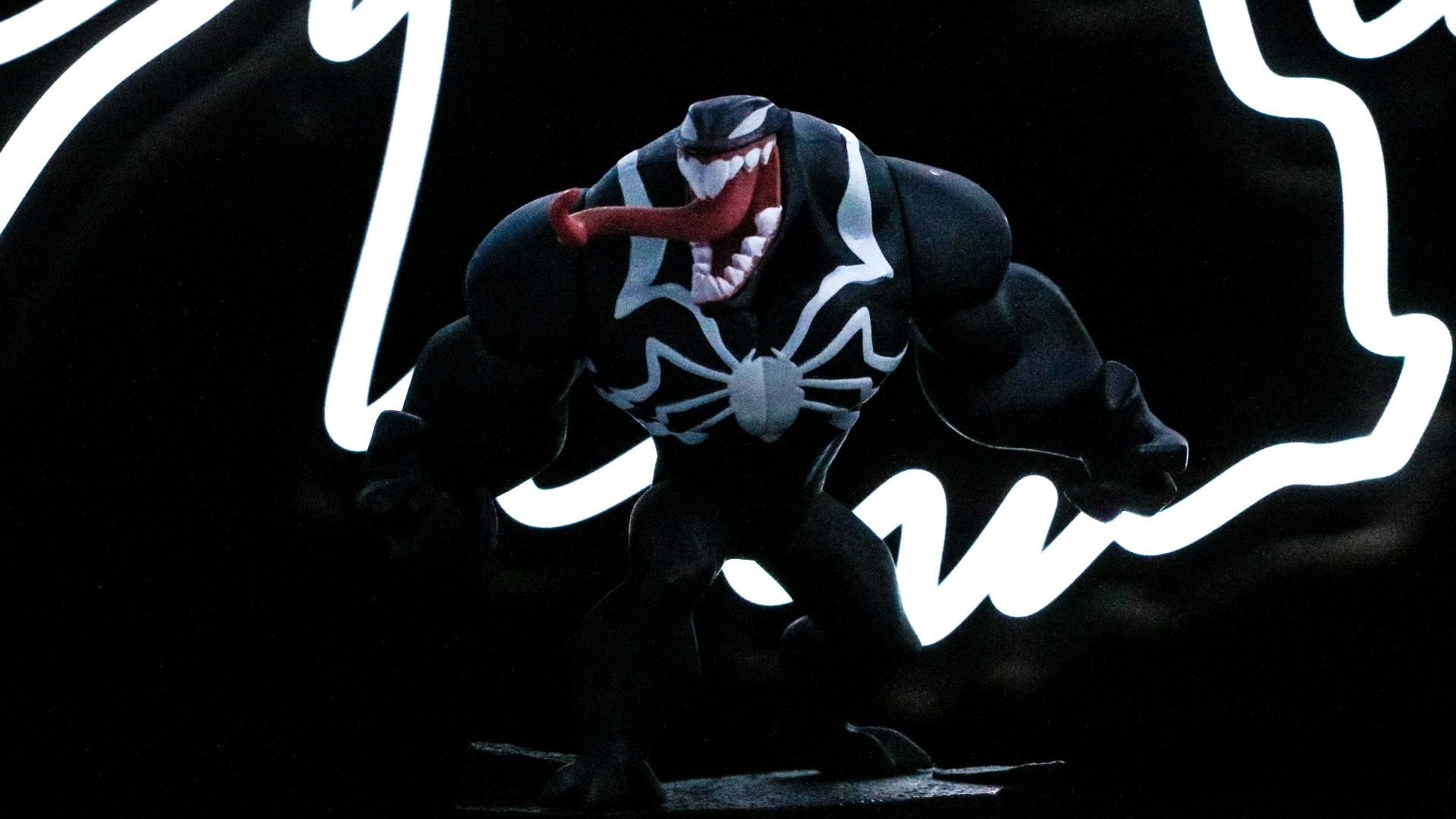 a spider - man figure is posed in front of a neon sign