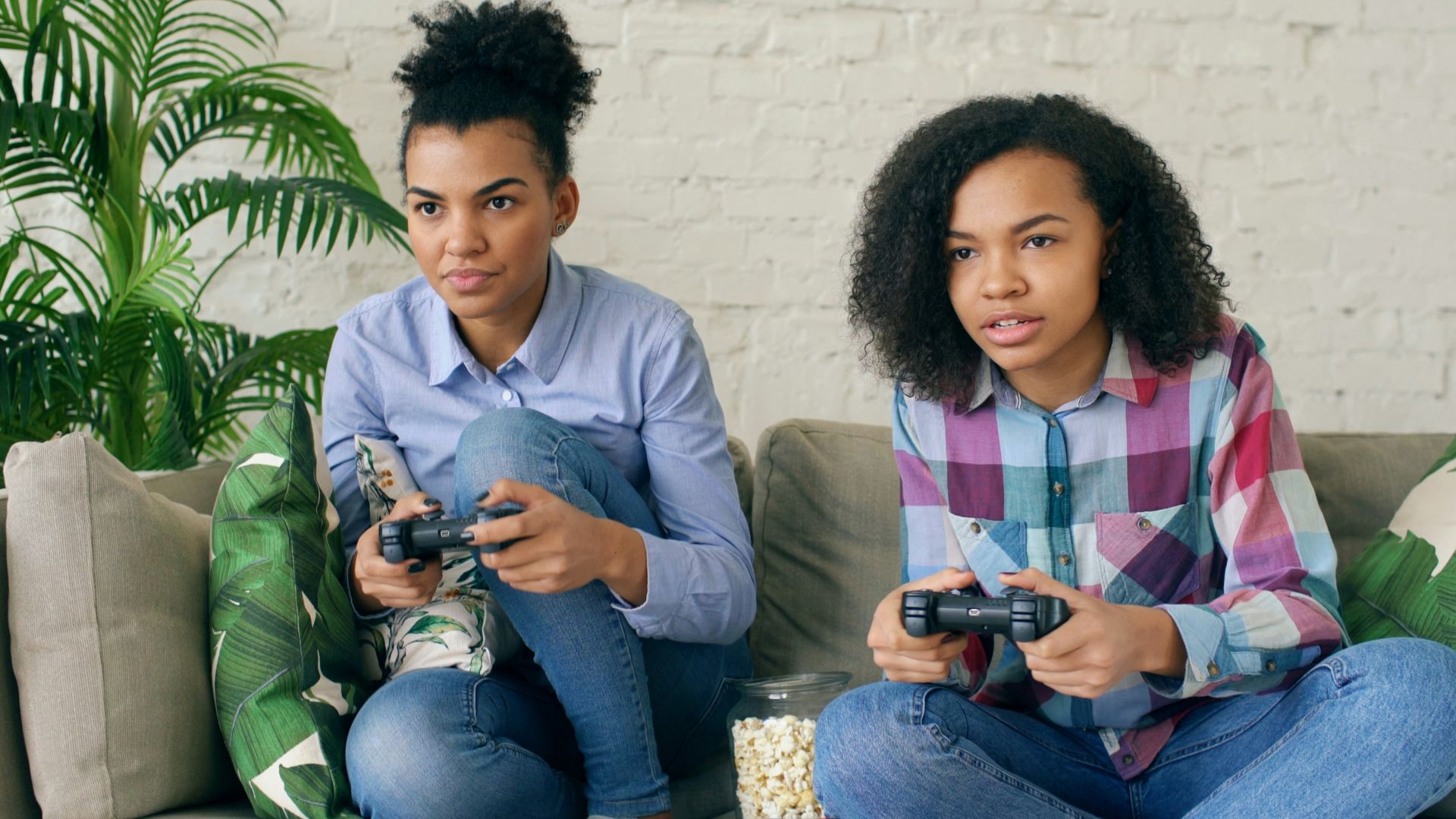 Two women playing video games on a couch.