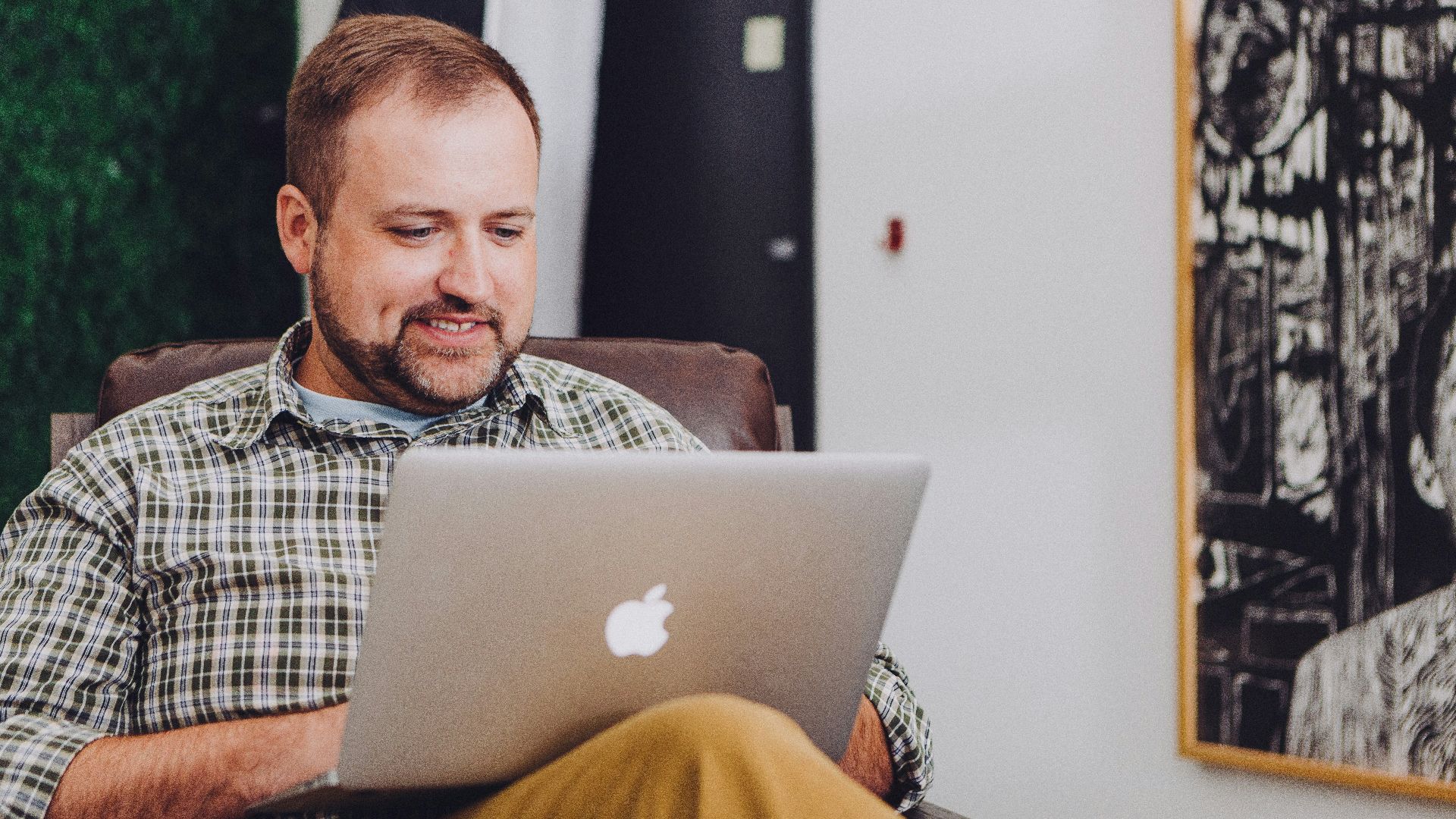 man smiling and using MacBook