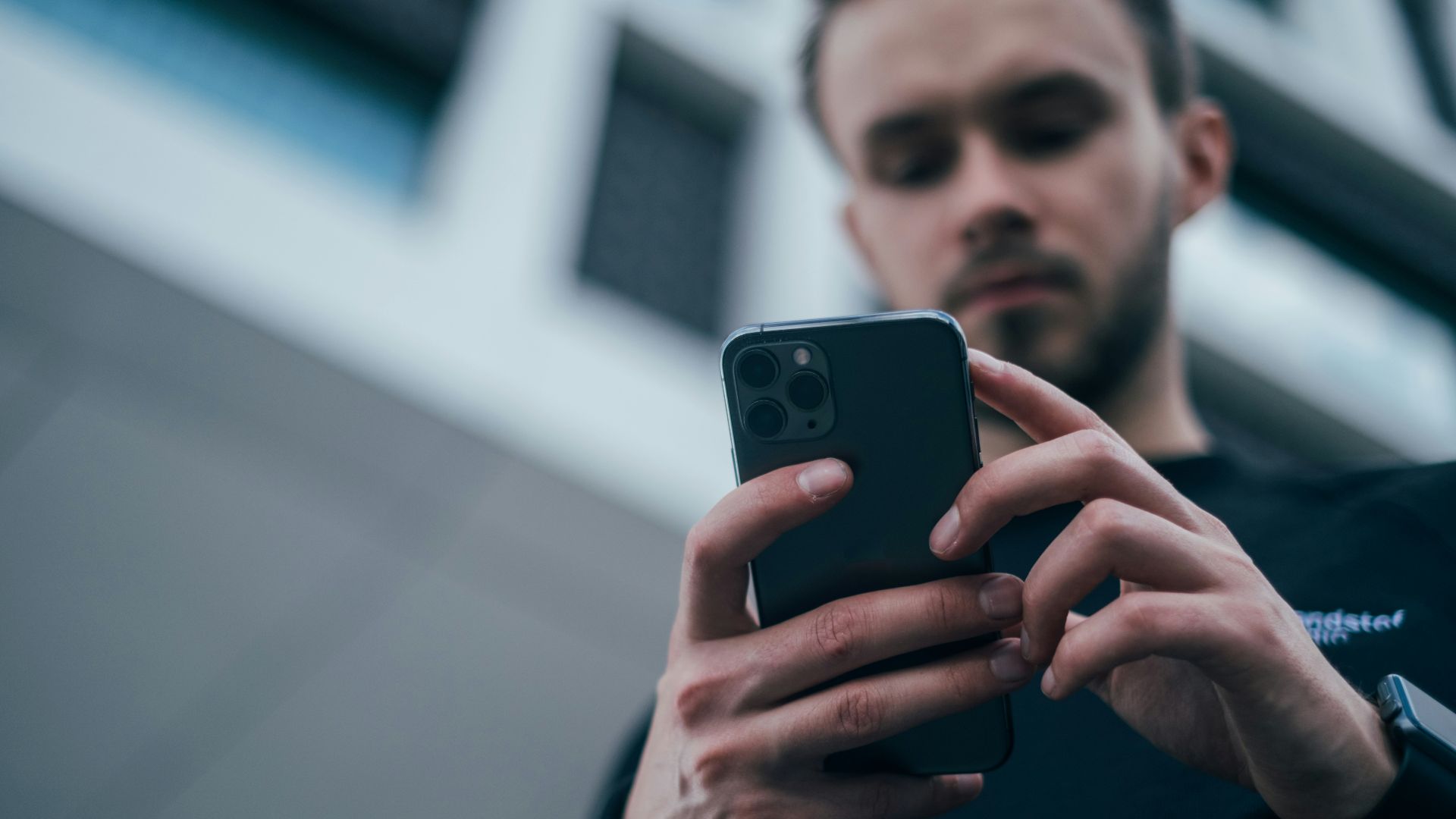 man wearing black sweater using smartphone