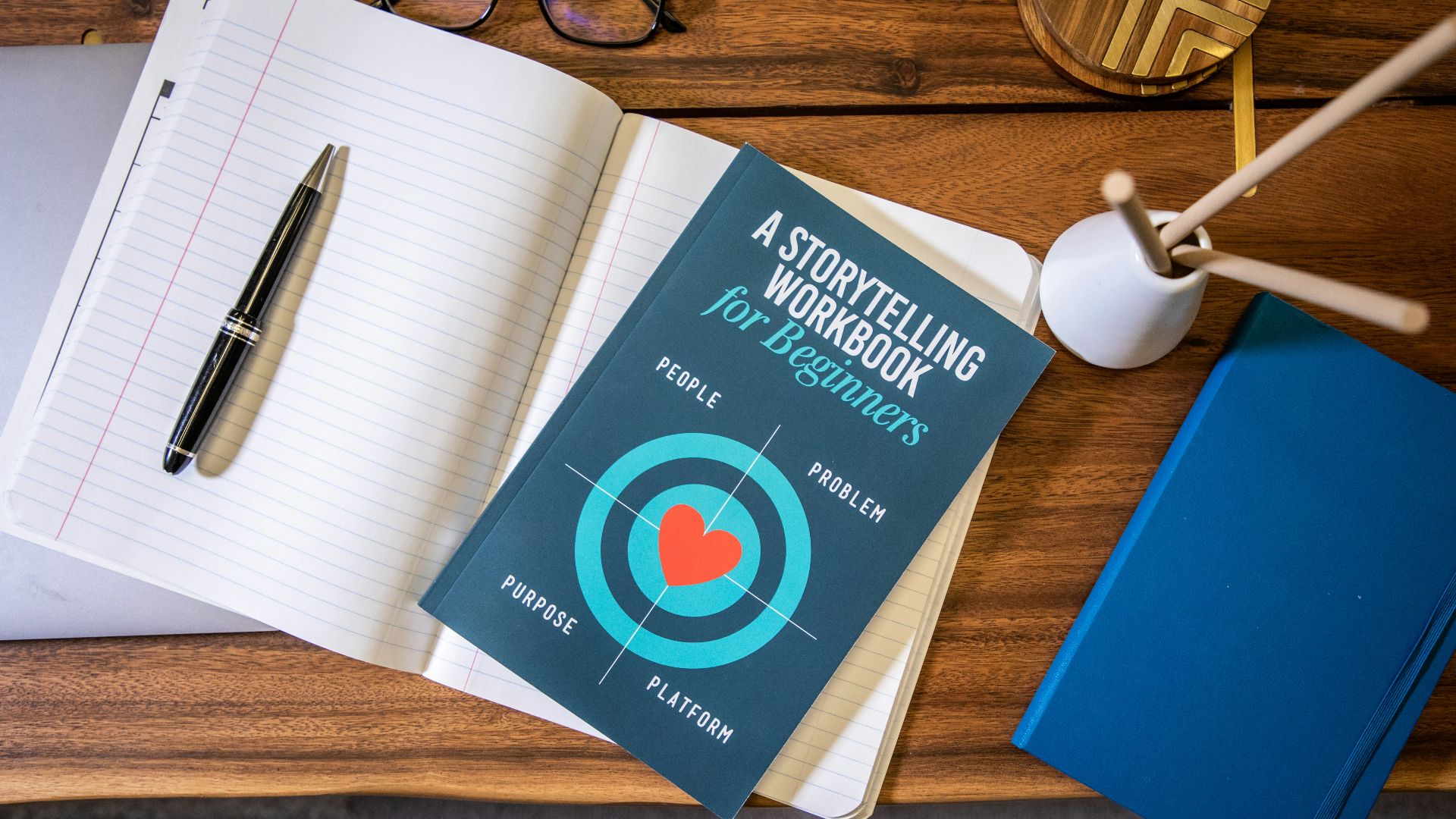 a notebook, pen, eyeglasses, and a cup of coffee on a