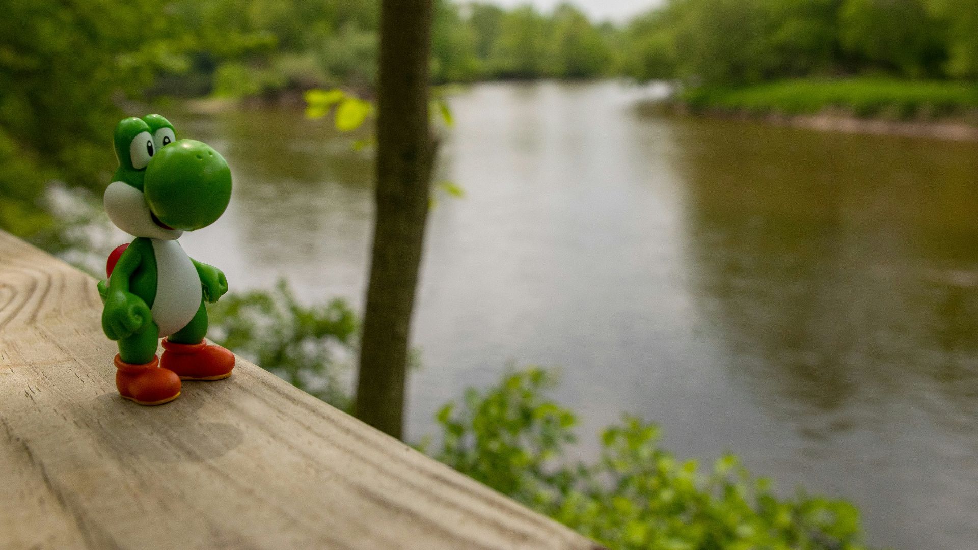 a toy figure is sitting on a ledge near a river