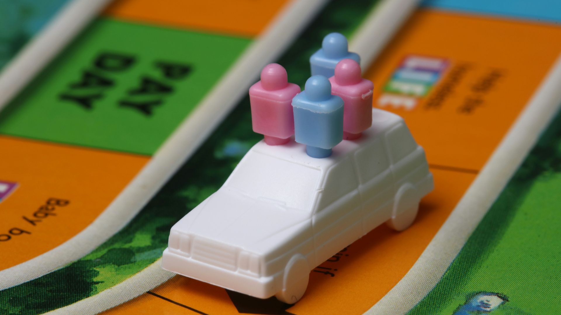 white and blue car toy on top of orange game board