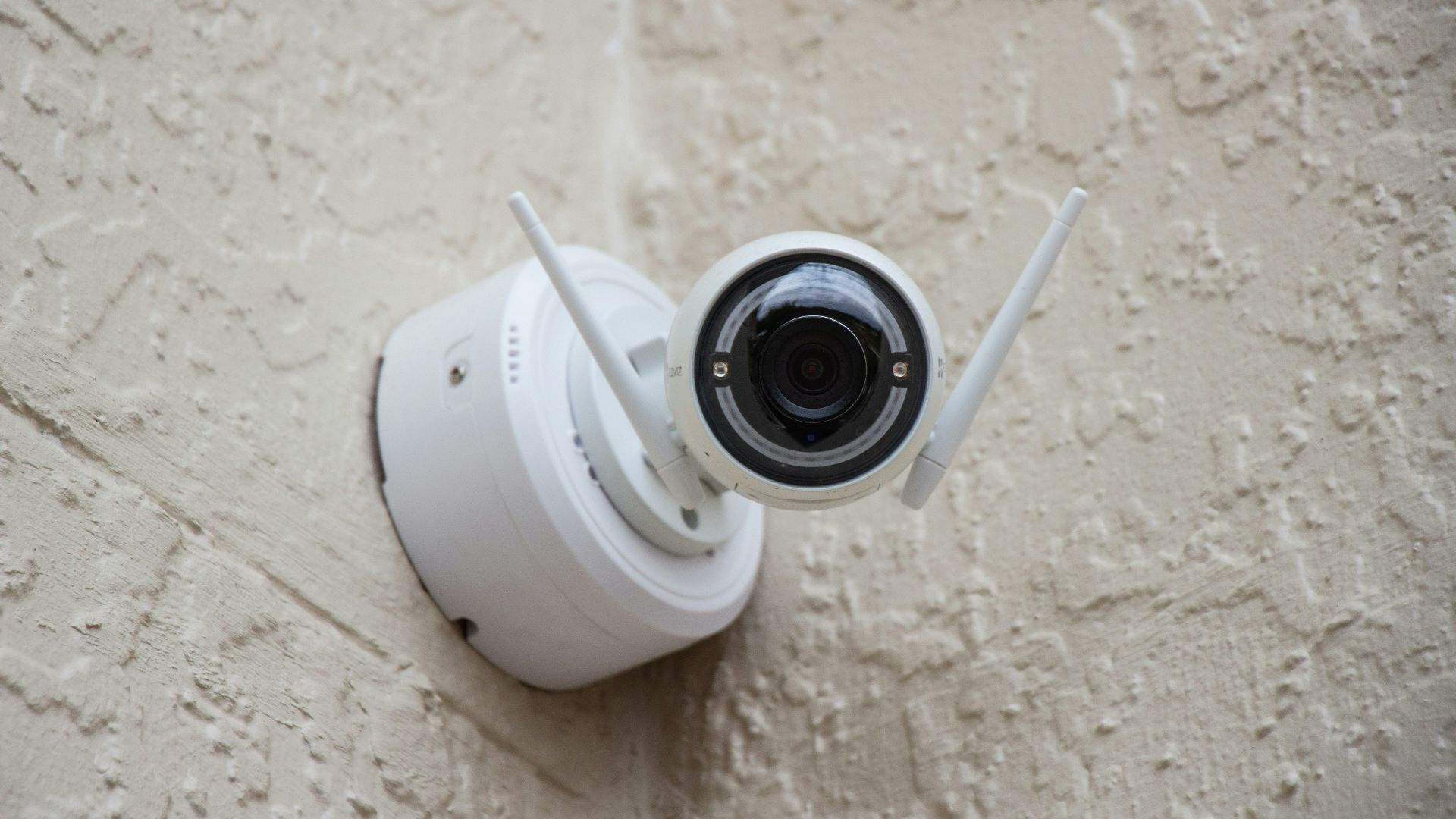 white surveillance camera hanging on wall