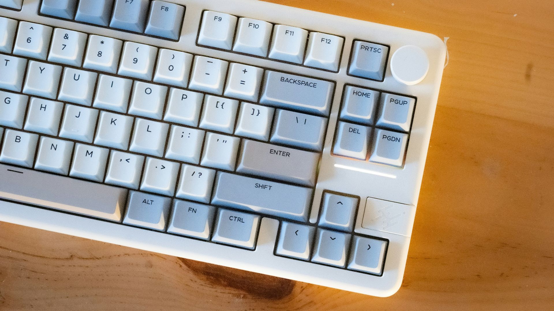 A white mechanical keyboard rests on a wooden surface.
