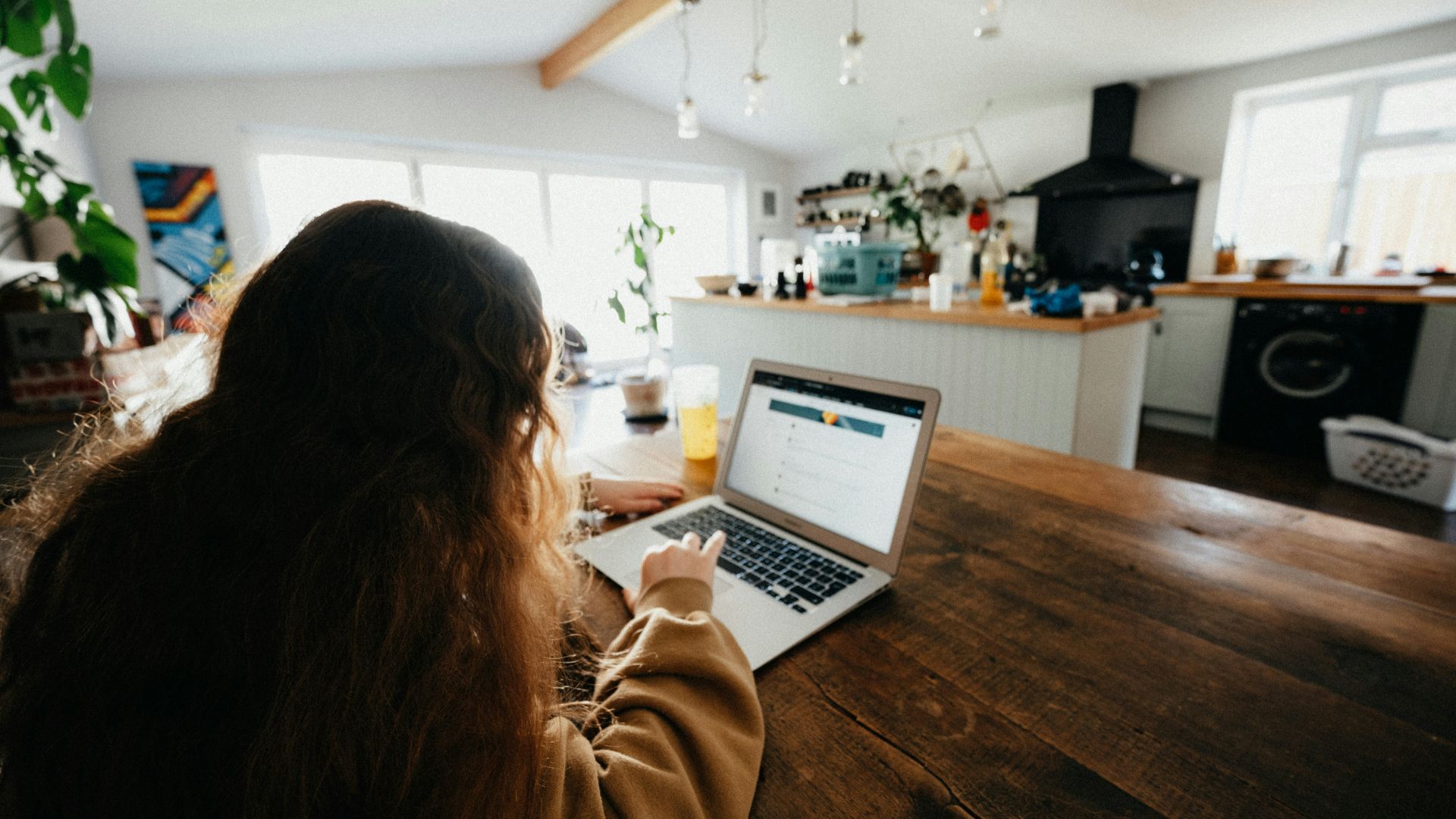 woman in brown sweater using macbook pro