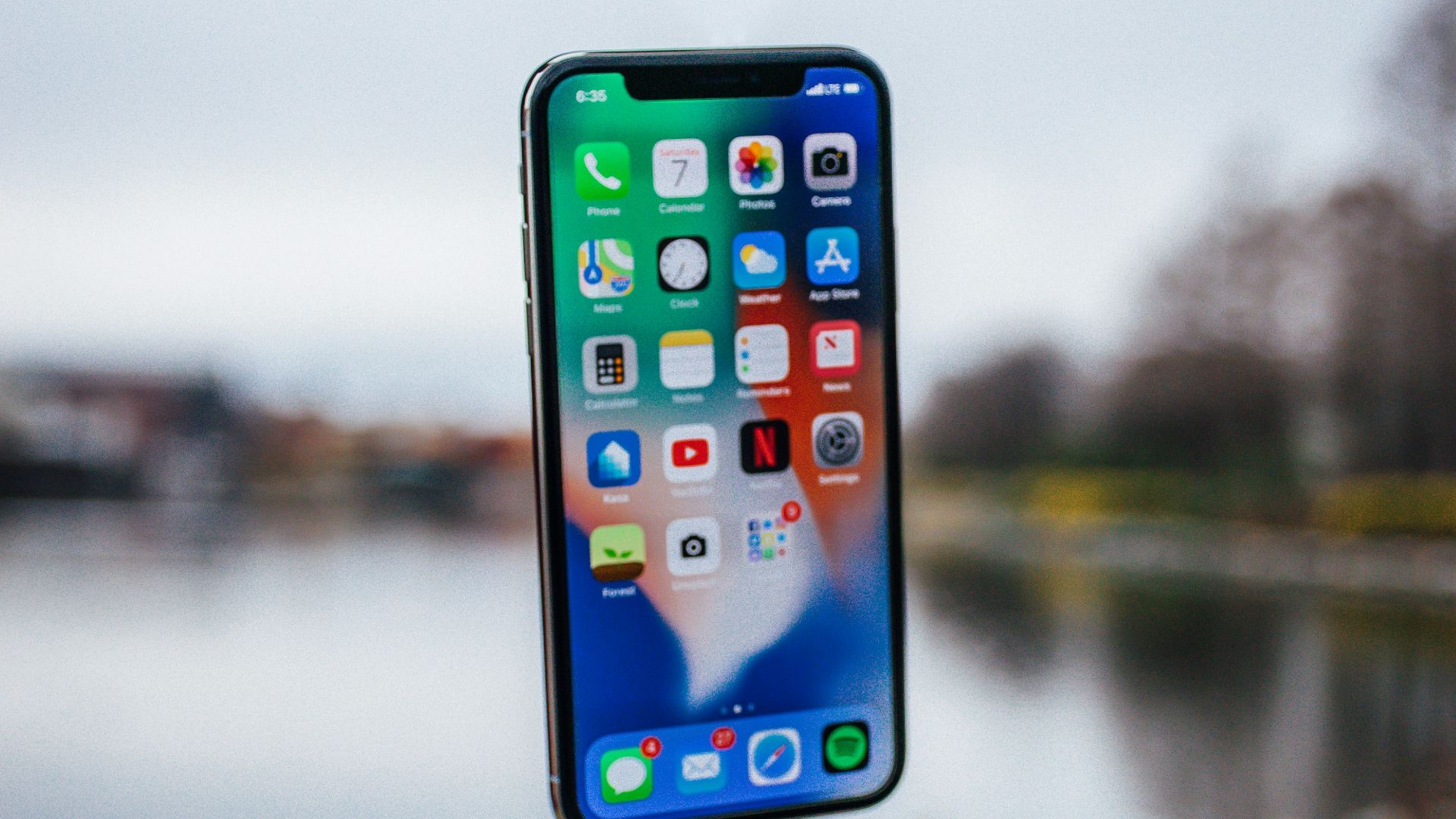 silver iPhone X floating over open palm
