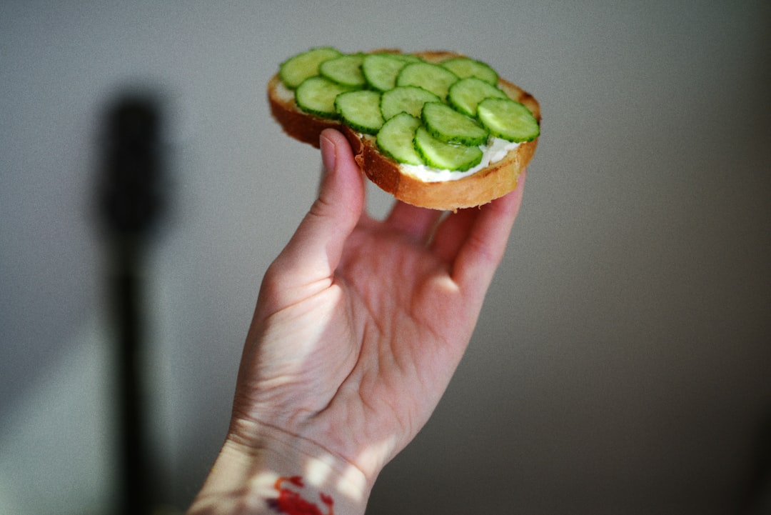 a person holding a sandwich with cucumbers on it