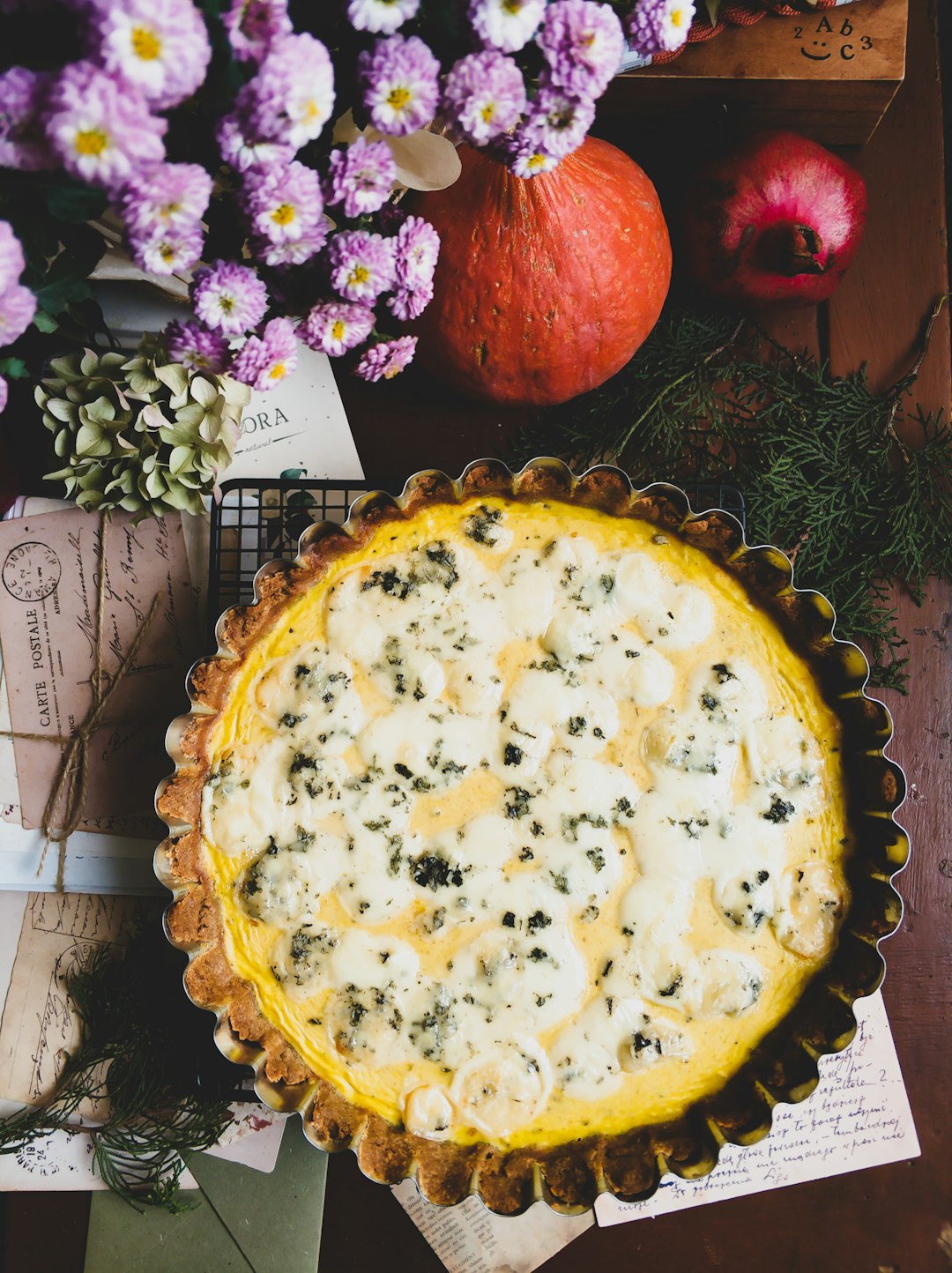 A pie sitting on top of a wooden table next to flowers