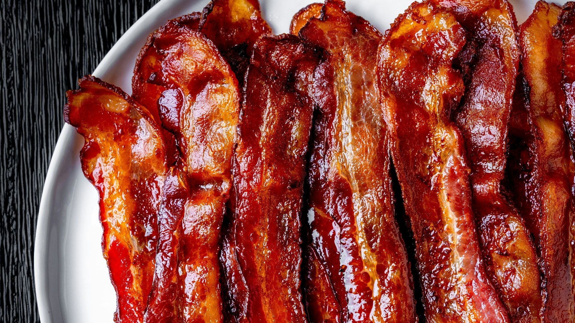 a white plate topped with bacon strips on top of a table