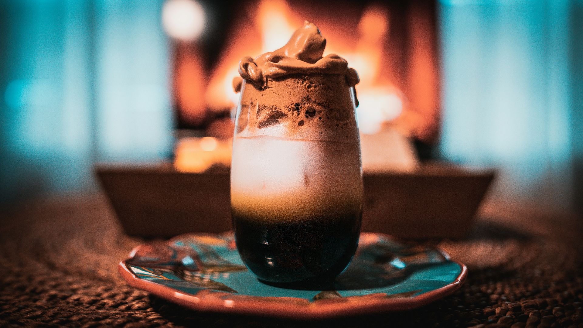 clear drinking glass with black liquid on blue ceramic saucer