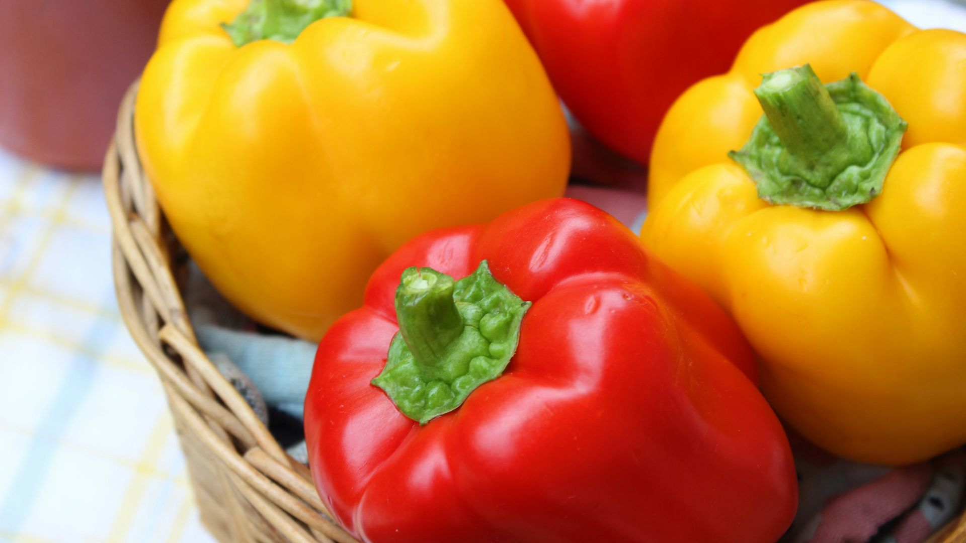red and yellow bell peppers in brown woven basket