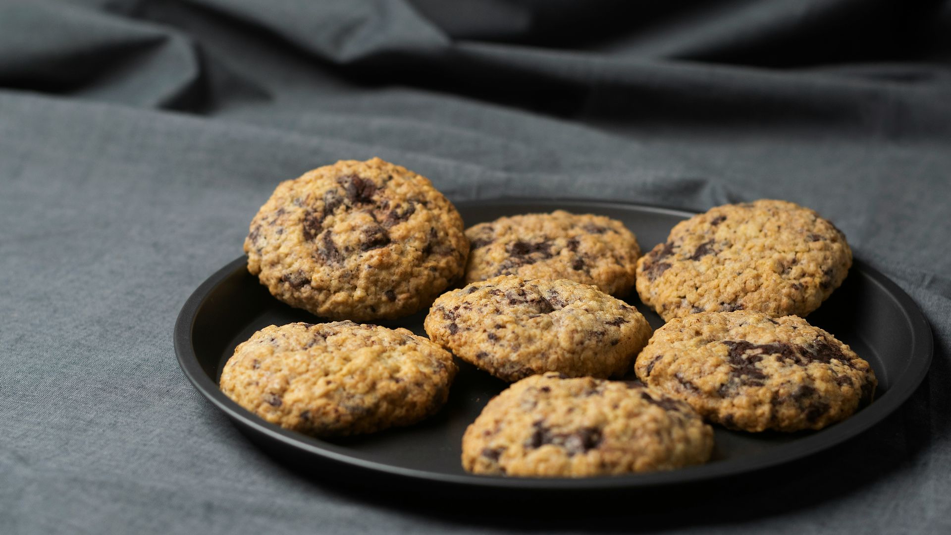 a plate of chocolate chip cookies on a gray cloth