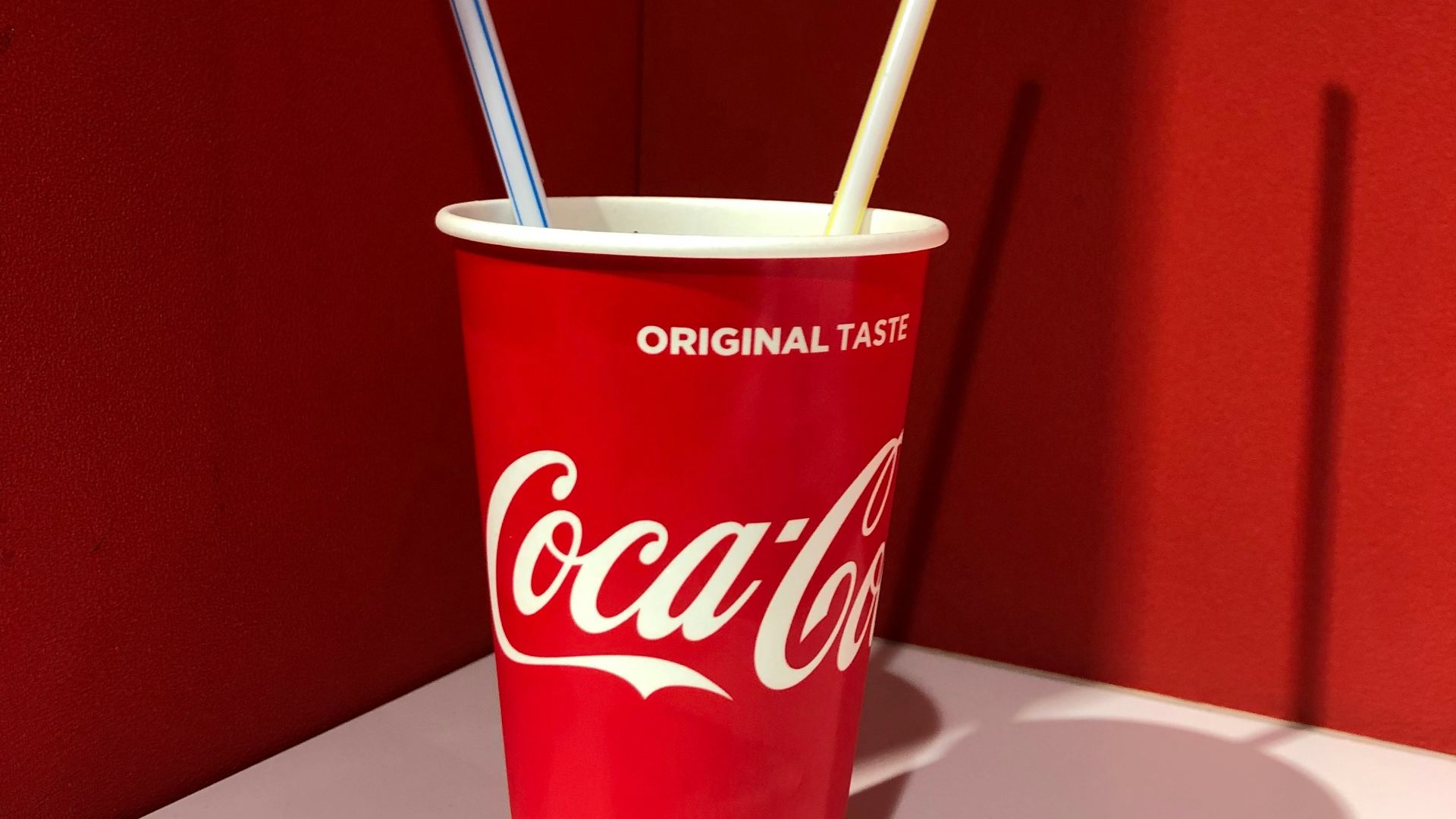 Coca-Cola disposable cup on top of white table