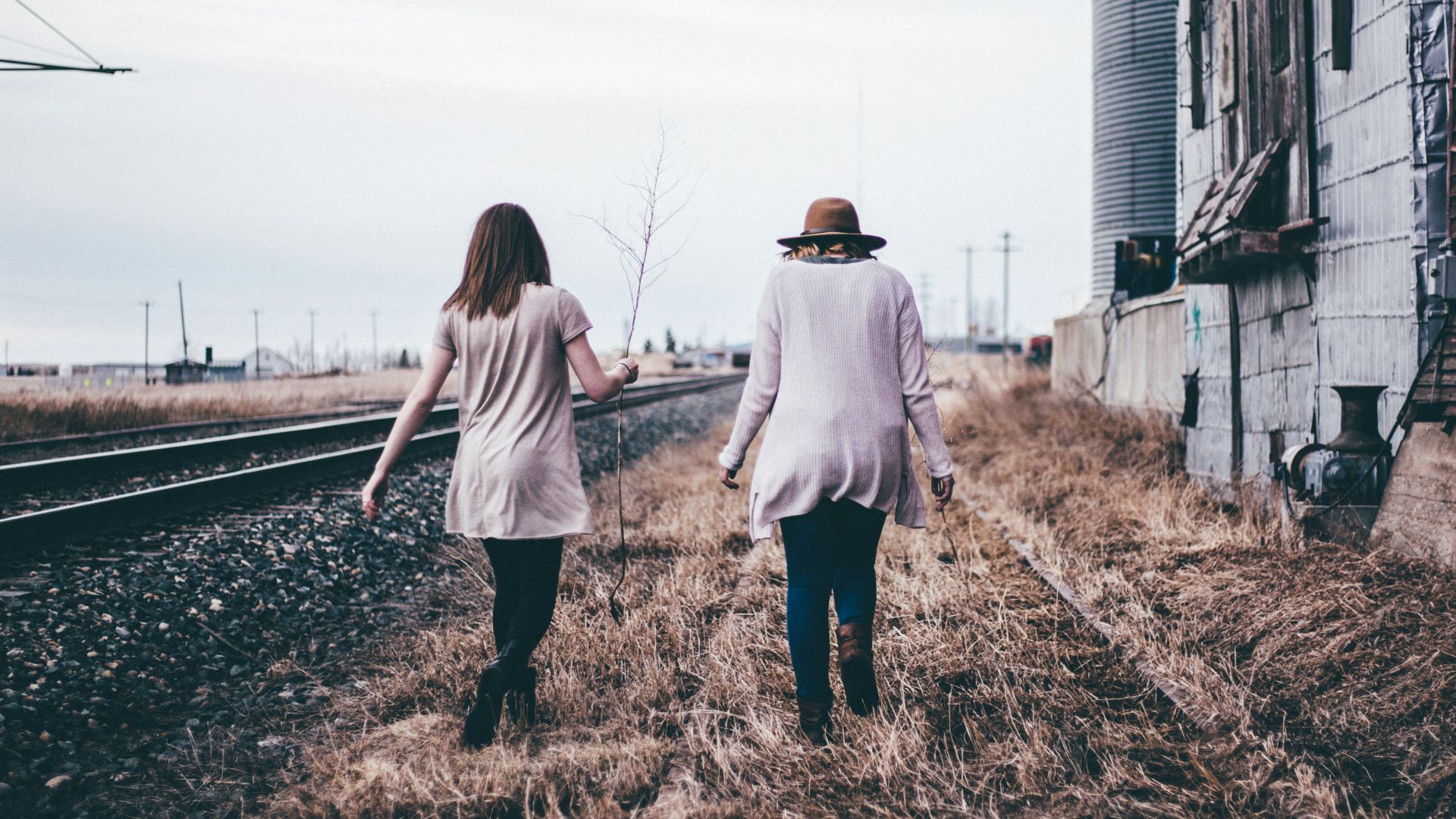 photo of two persons walking along railway