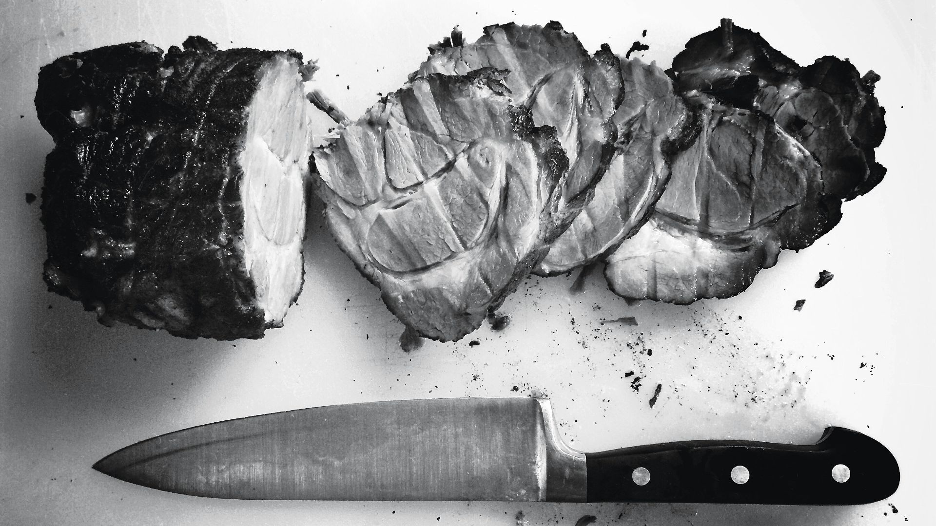 grayscale photo of grilled meat beside knife and fork