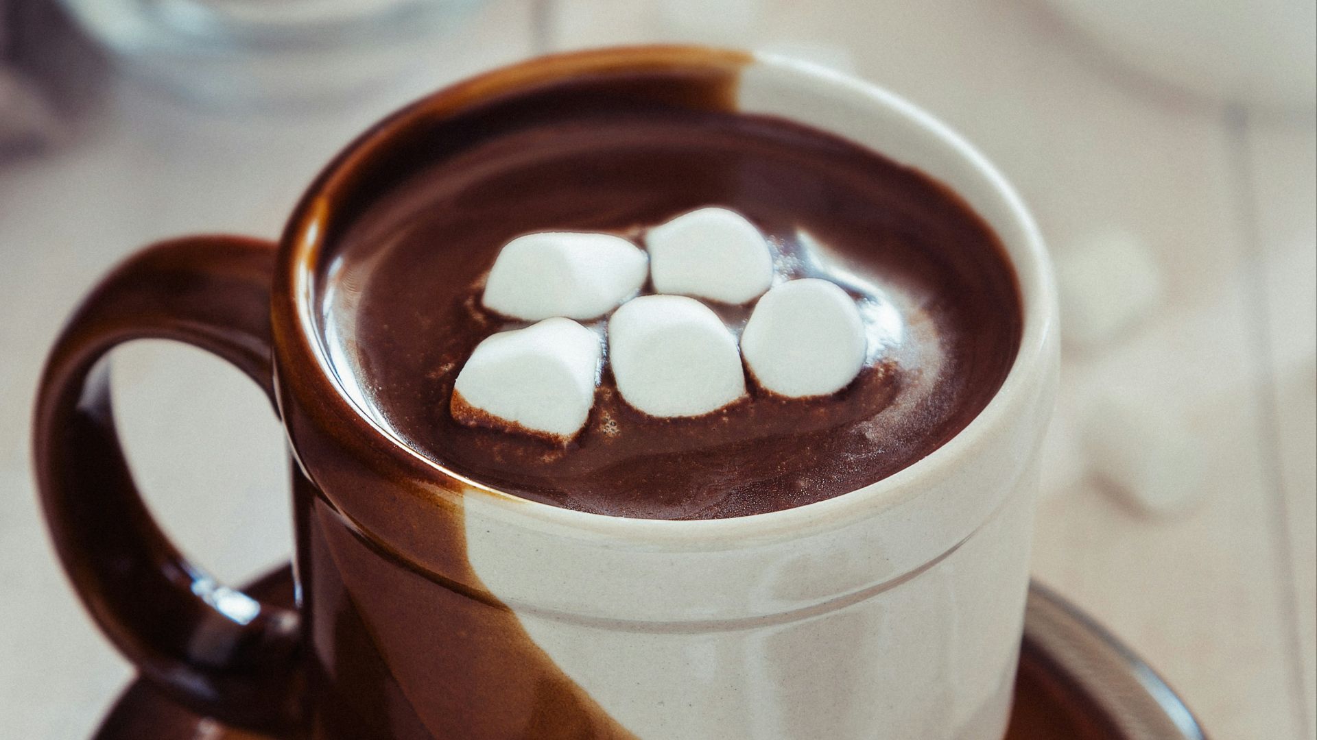 a cup of hot chocolate with marshmallows on a saucer
