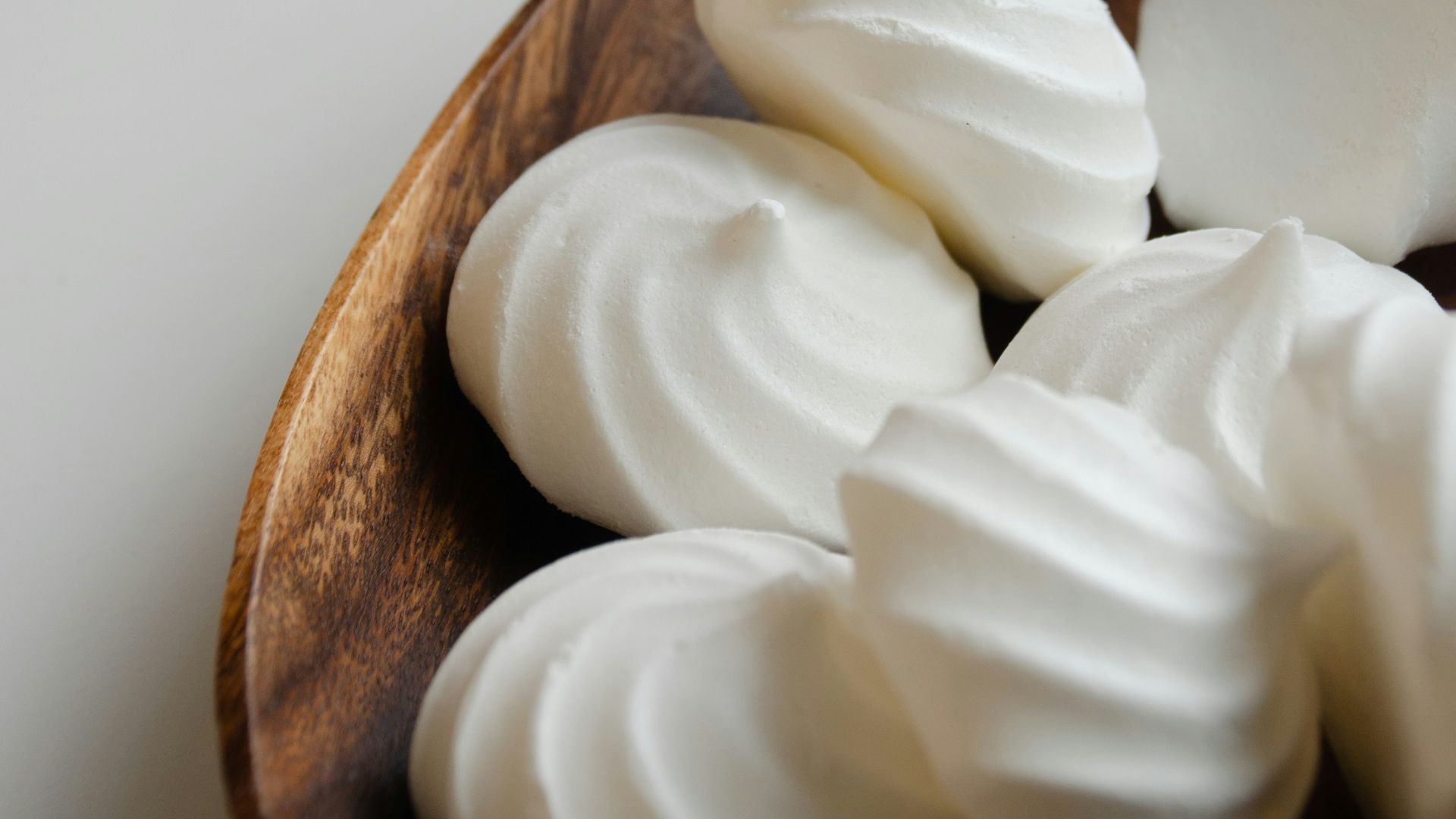 a wooden bowl filled with whipped cream on top of a table