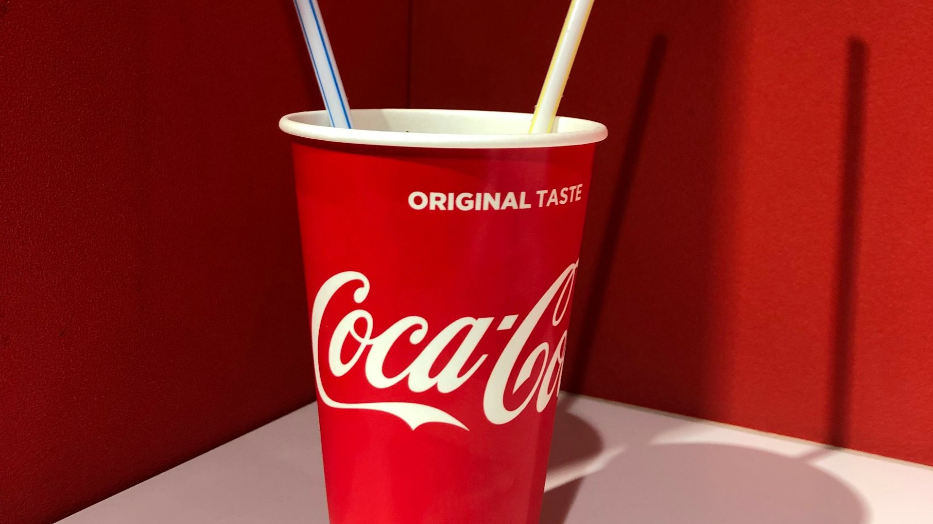 Coca-Cola disposable cup on top of white table