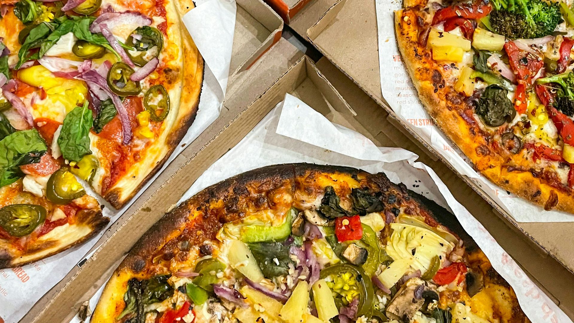 four pizzas with different toppings in a box