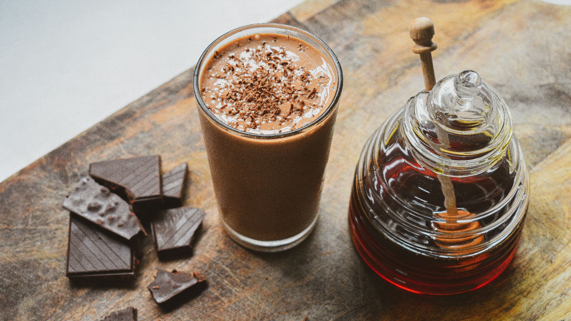 a glass of hot chocolate next to a jar of chocolate