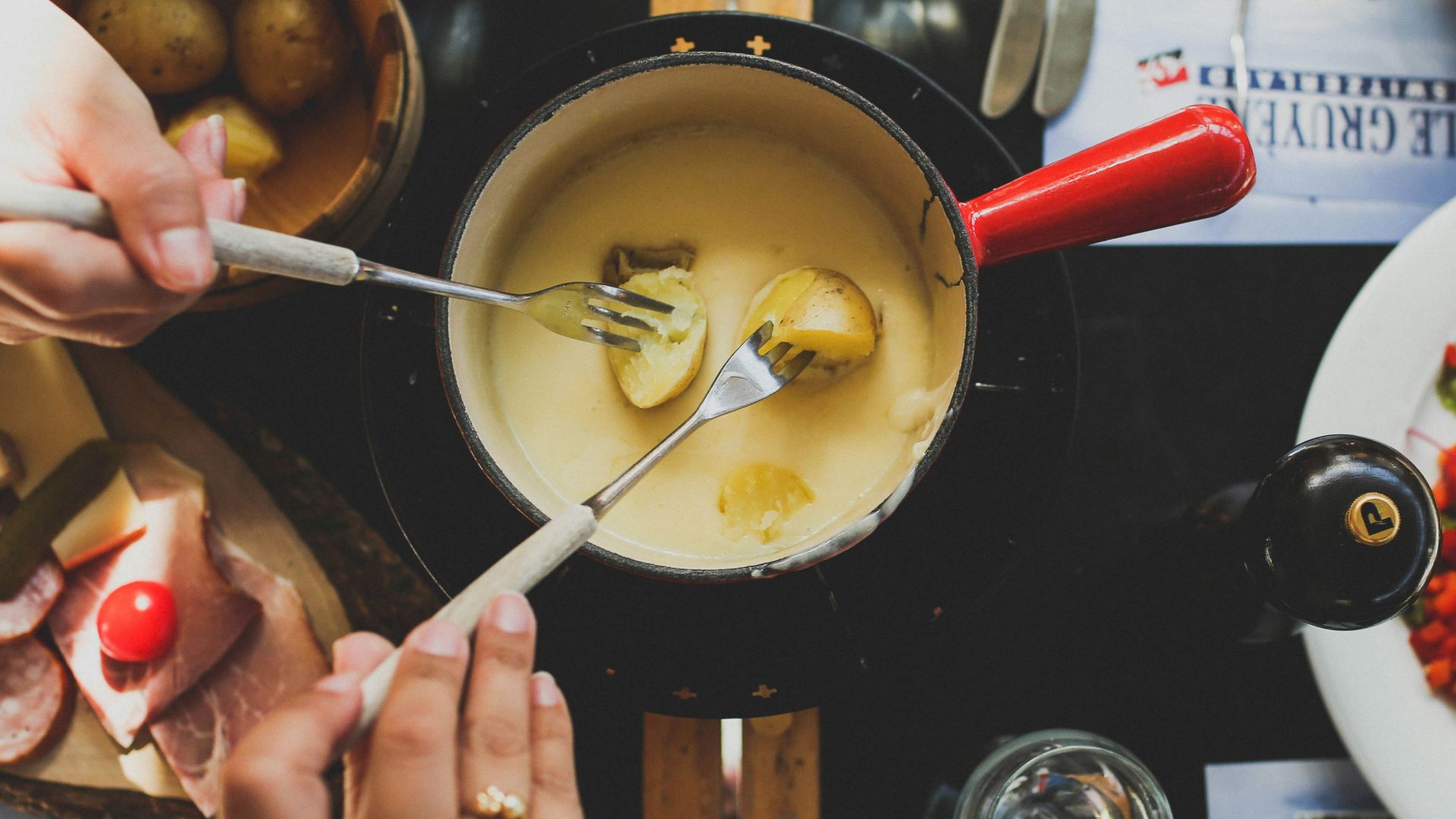 two person holding fork dipping food on sauce