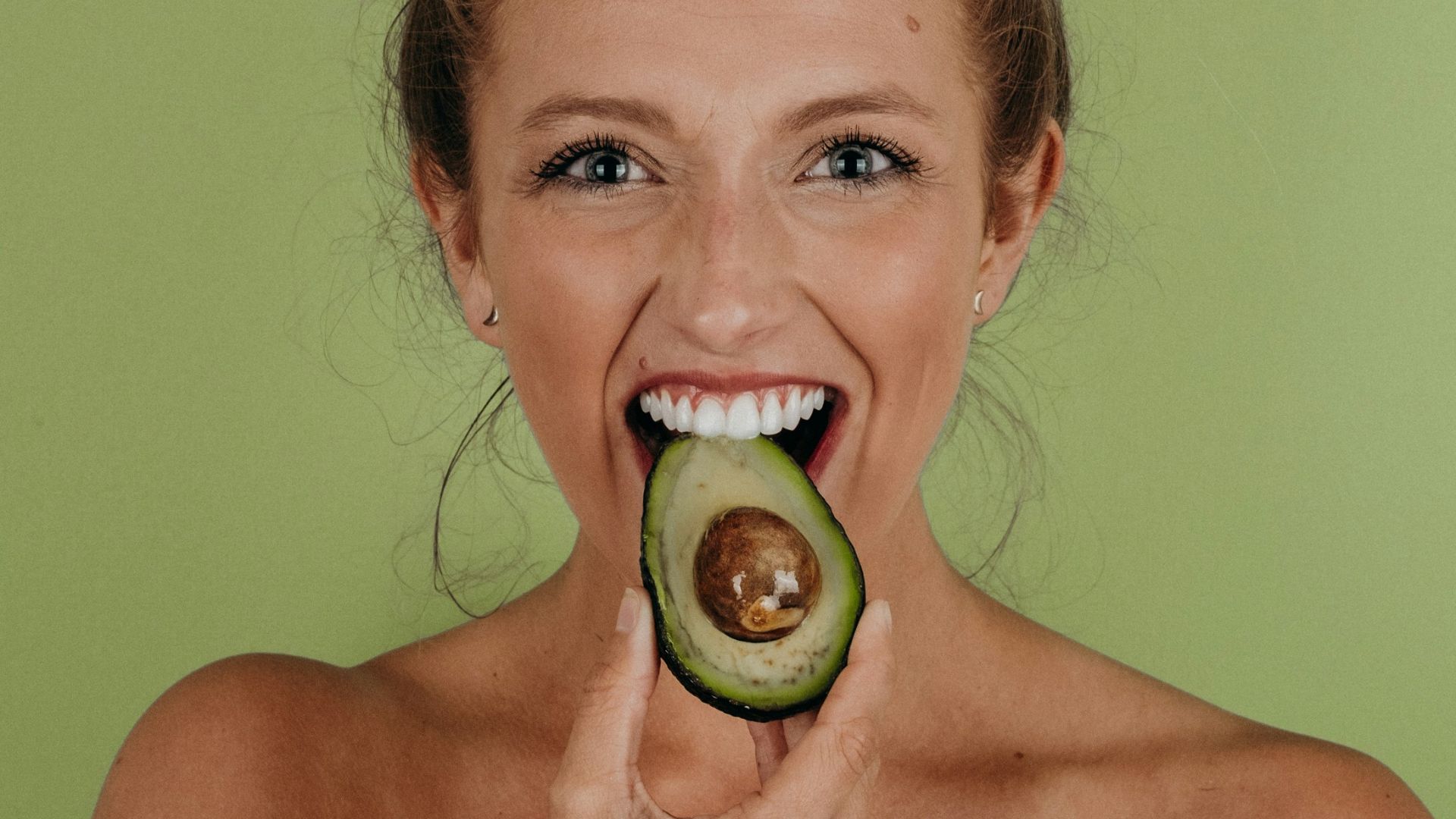 woman holding sliced avocado