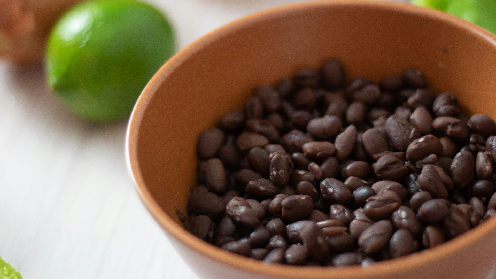 a bowl filled with black beans next to limes