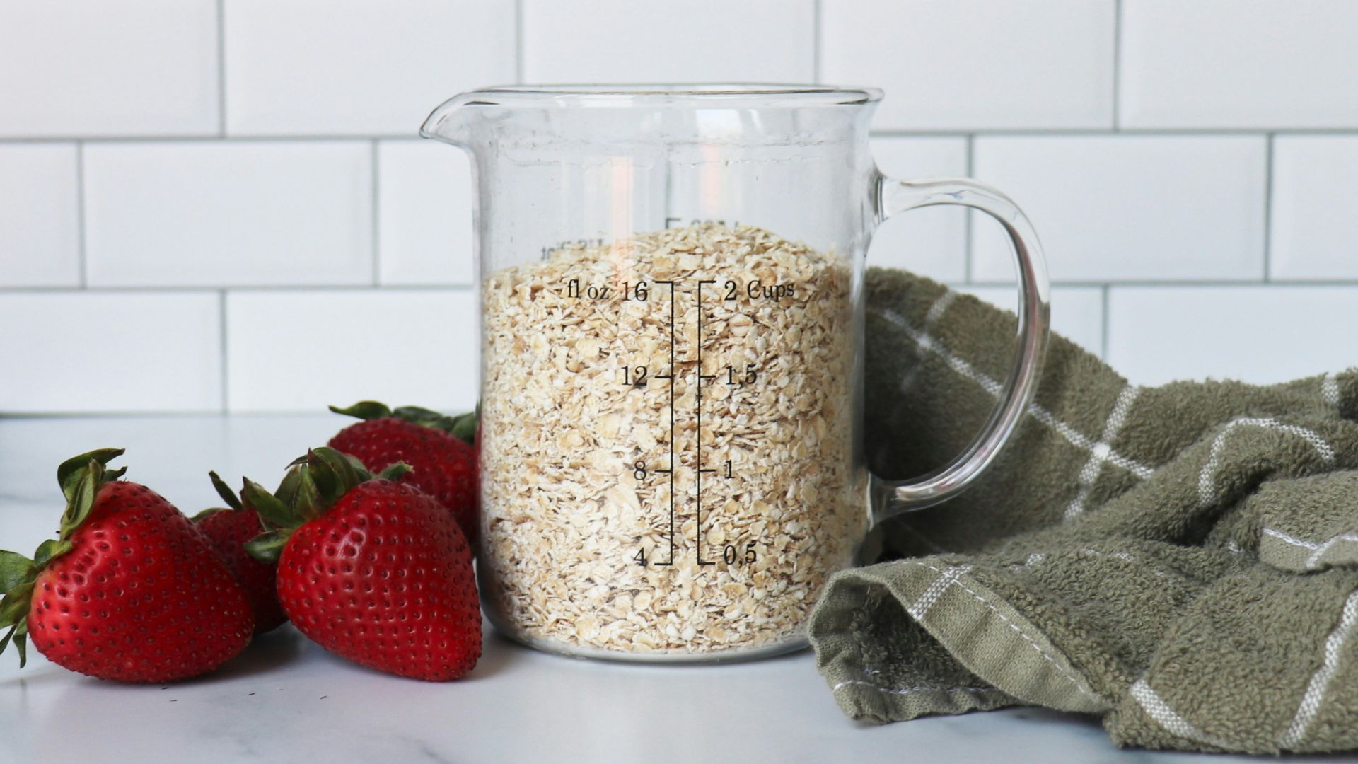 strawberries on white ceramic bowl beside clear glass pitcher