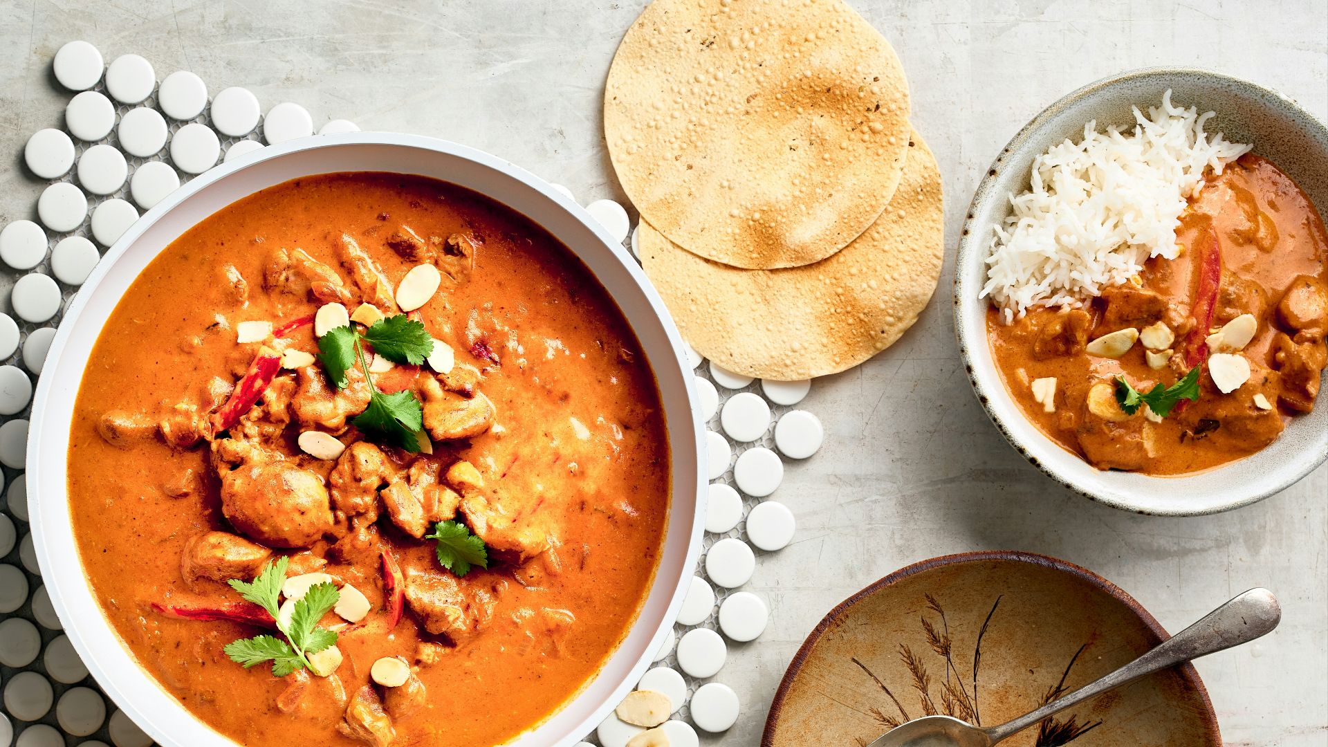 a bowl of red curry next to a bowl of rice and a bowl of soup