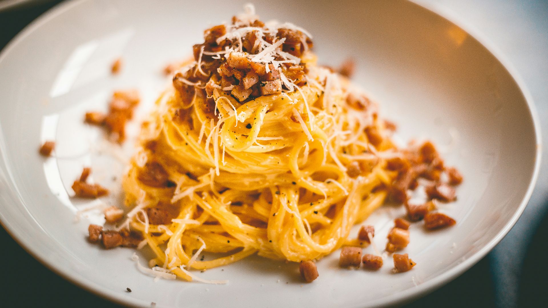 a white plate topped with spaghetti and bacon